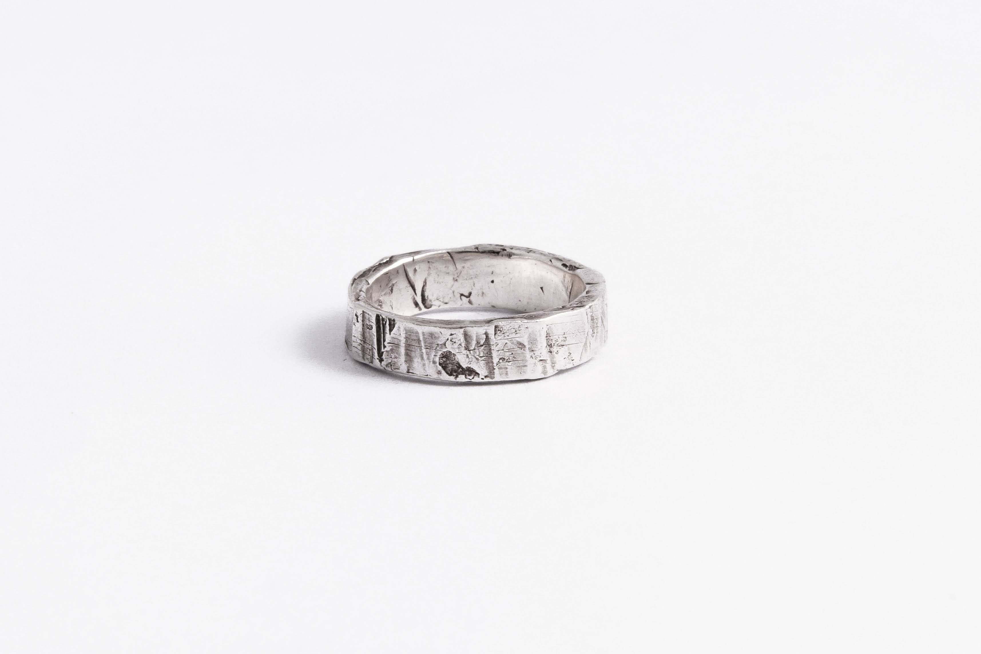 Flat sterling silver ring with raw scratched, cut and filed surface – top view.
