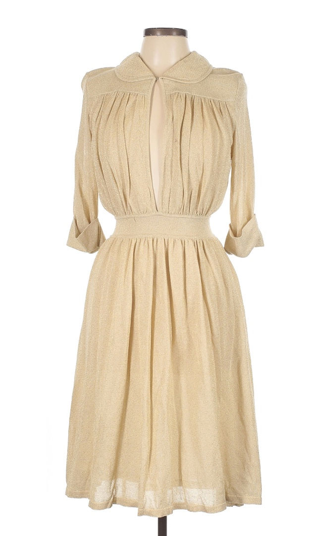 Beige vintage dress on a mannequin, featuring a pleated design, keyhole neckline, and cuffed sleeves, set against a plain background.