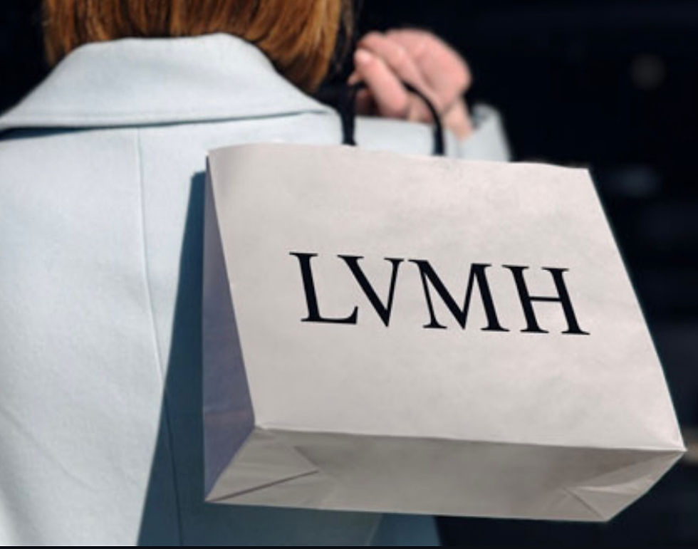 Person in a light blue coat carries a white shopping bag with "LVMH" printed on it. Dark background suggests an outdoor setting.