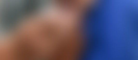 Enfermeiro aplica injeção no braço de uma pessoa com camiseta azul. O fundo é desfocado, focando na vacinação.