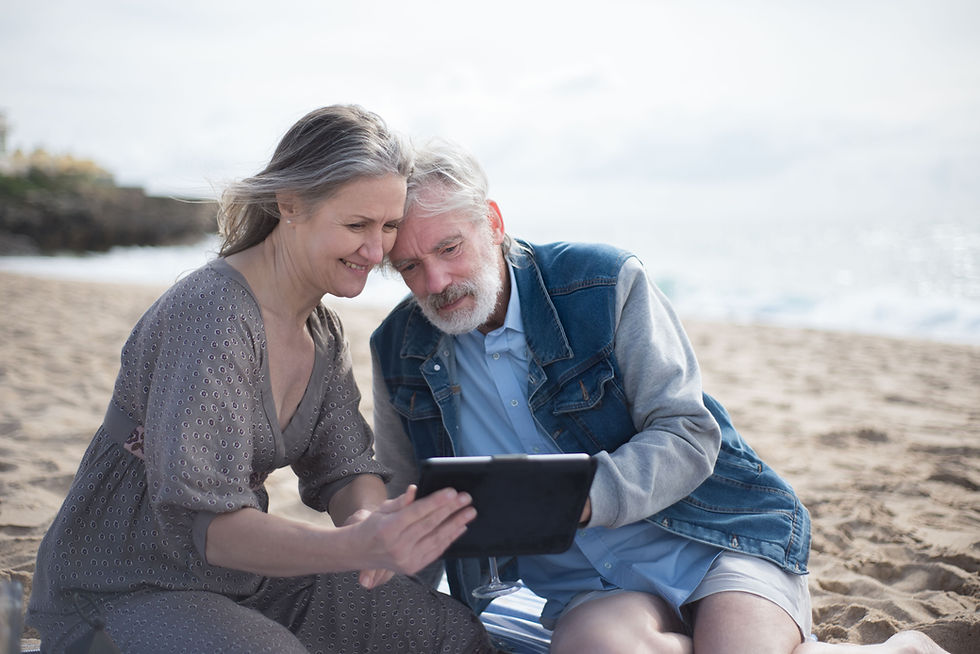 Senior couple using a tablet together on a sandy beach