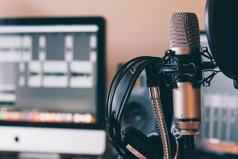 Home podcast recording setup with a condenser microphone, pop filter, over-ear headphones and a DAW on screen
