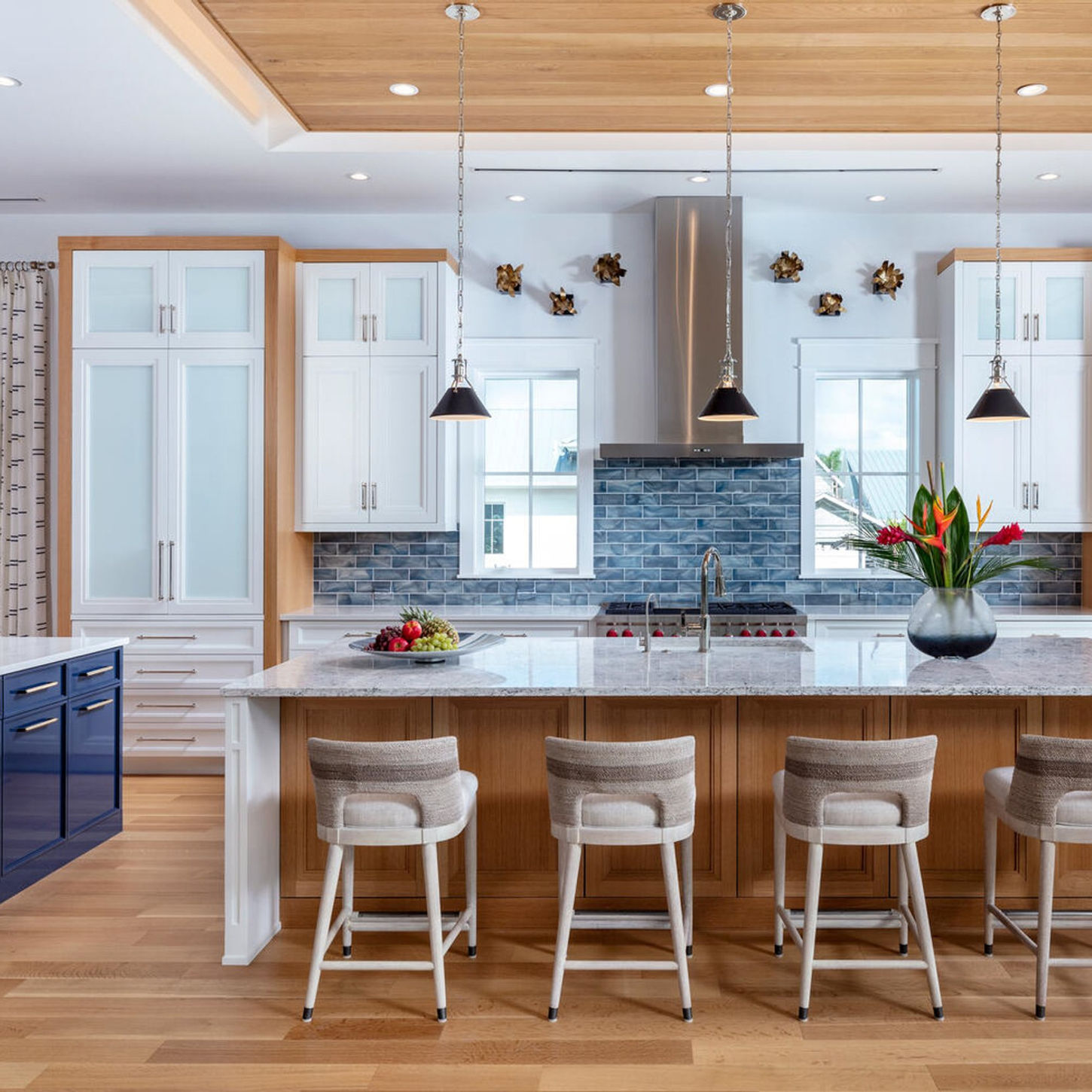 Luxury gourmet kitchen featuring white cabinetry, navy blue island, quartz countertops, and designer pendant lighting.