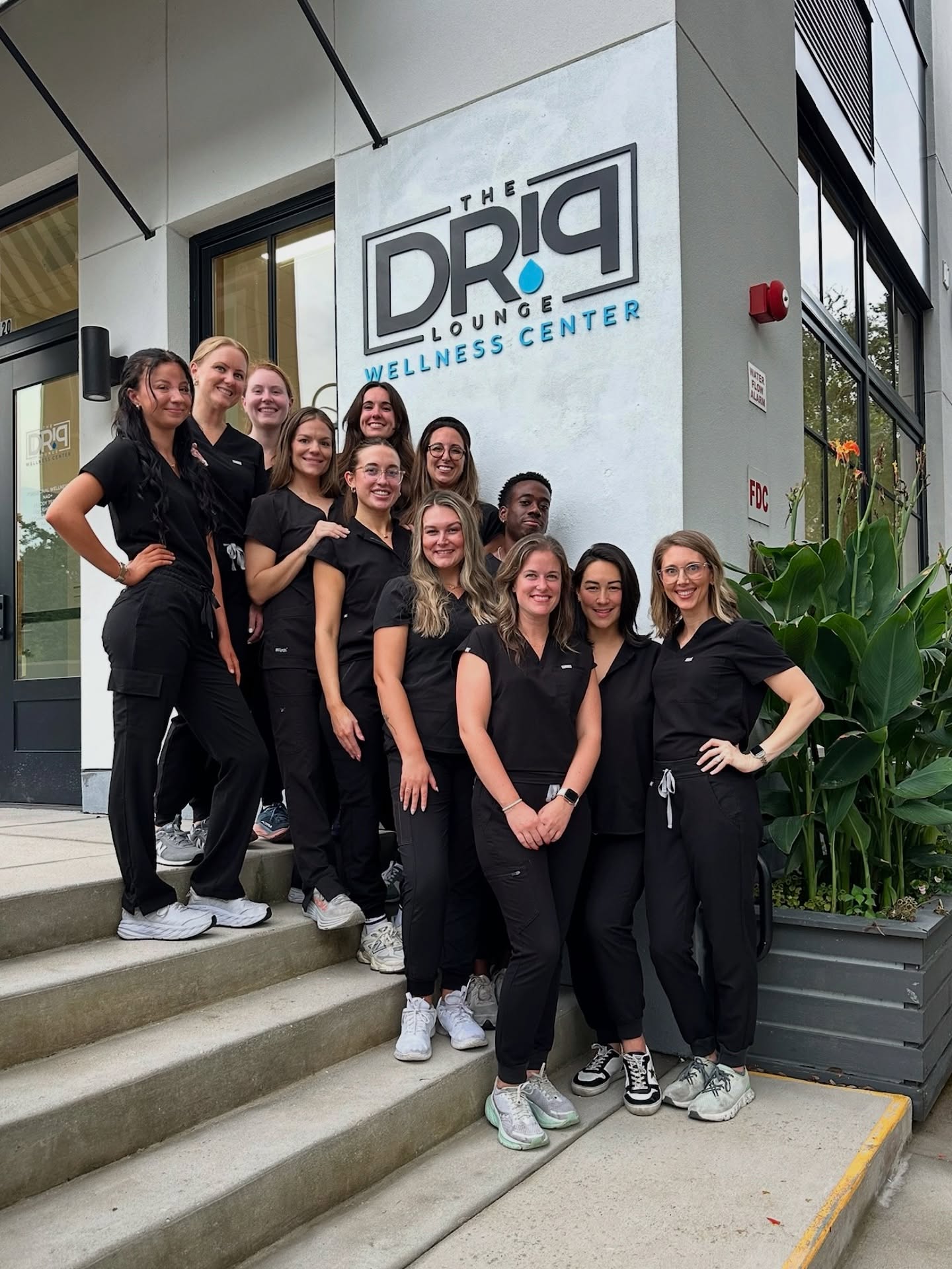 Group photo of The Drip Lounge staff standing on the front steps in black uniforms