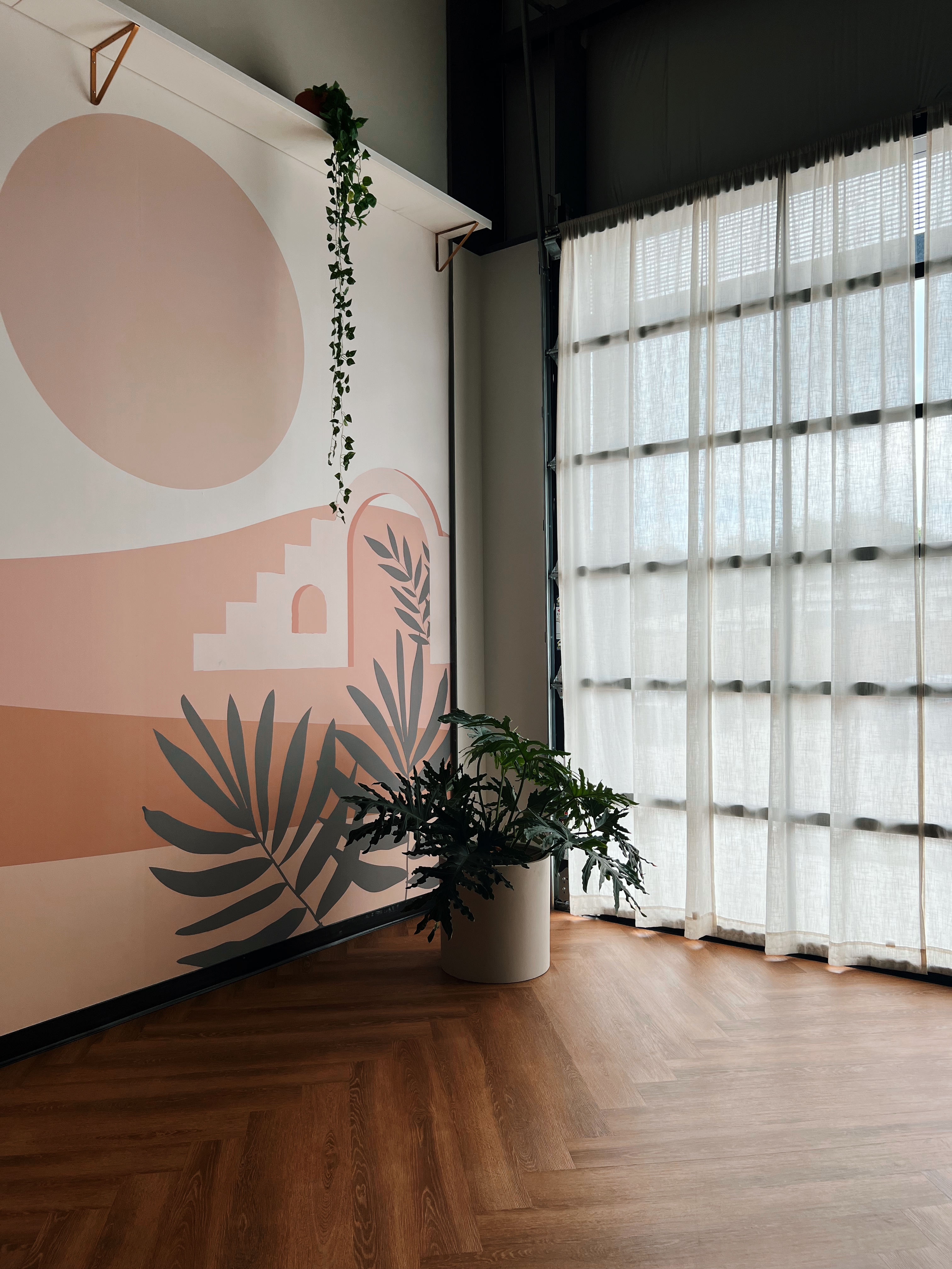 Pink desert mural, cactus, and glass-block wall inside My Vinyasa Practice Highland Austin yoga studio.