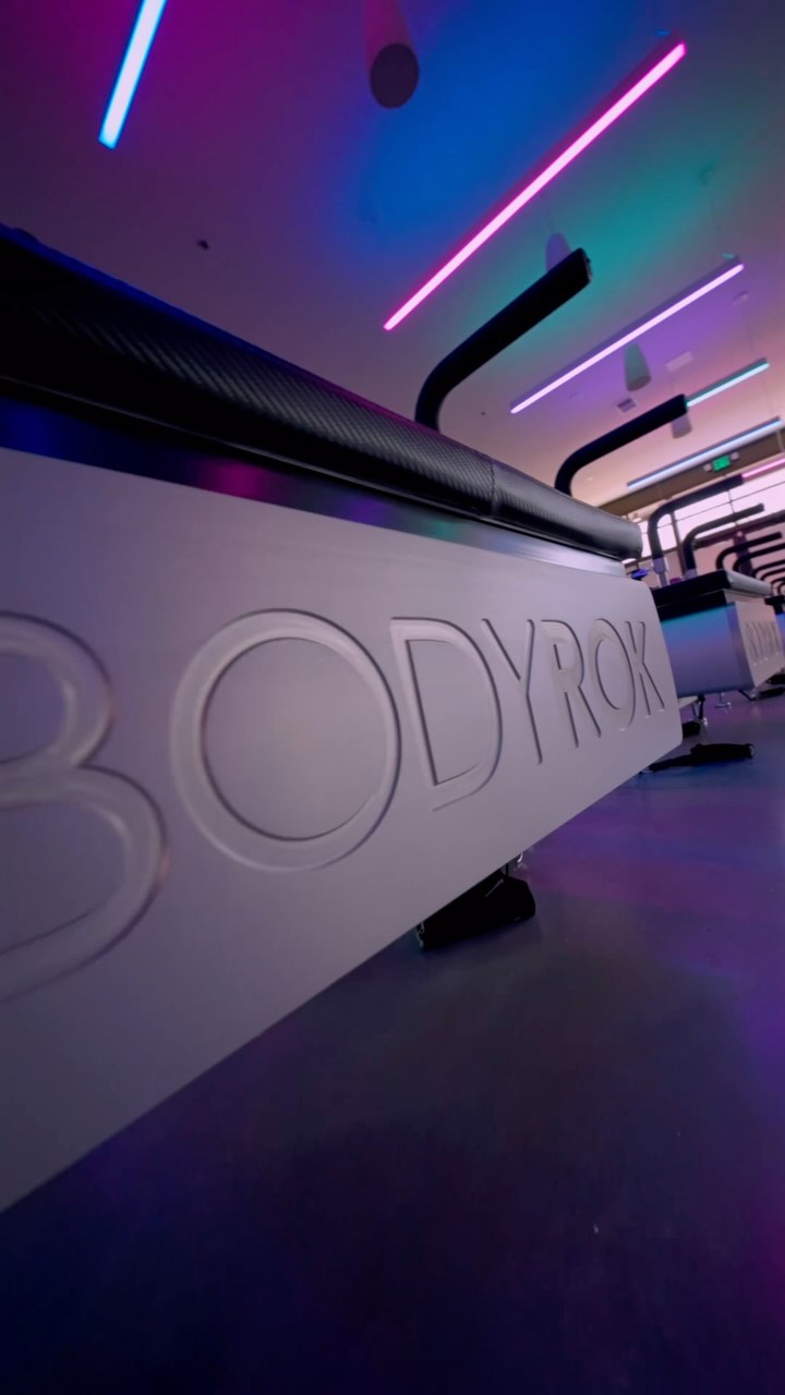 Neon hallway and reformer studio at BODYROK Inman Park Atlanta with illuminated BODYROK logo.