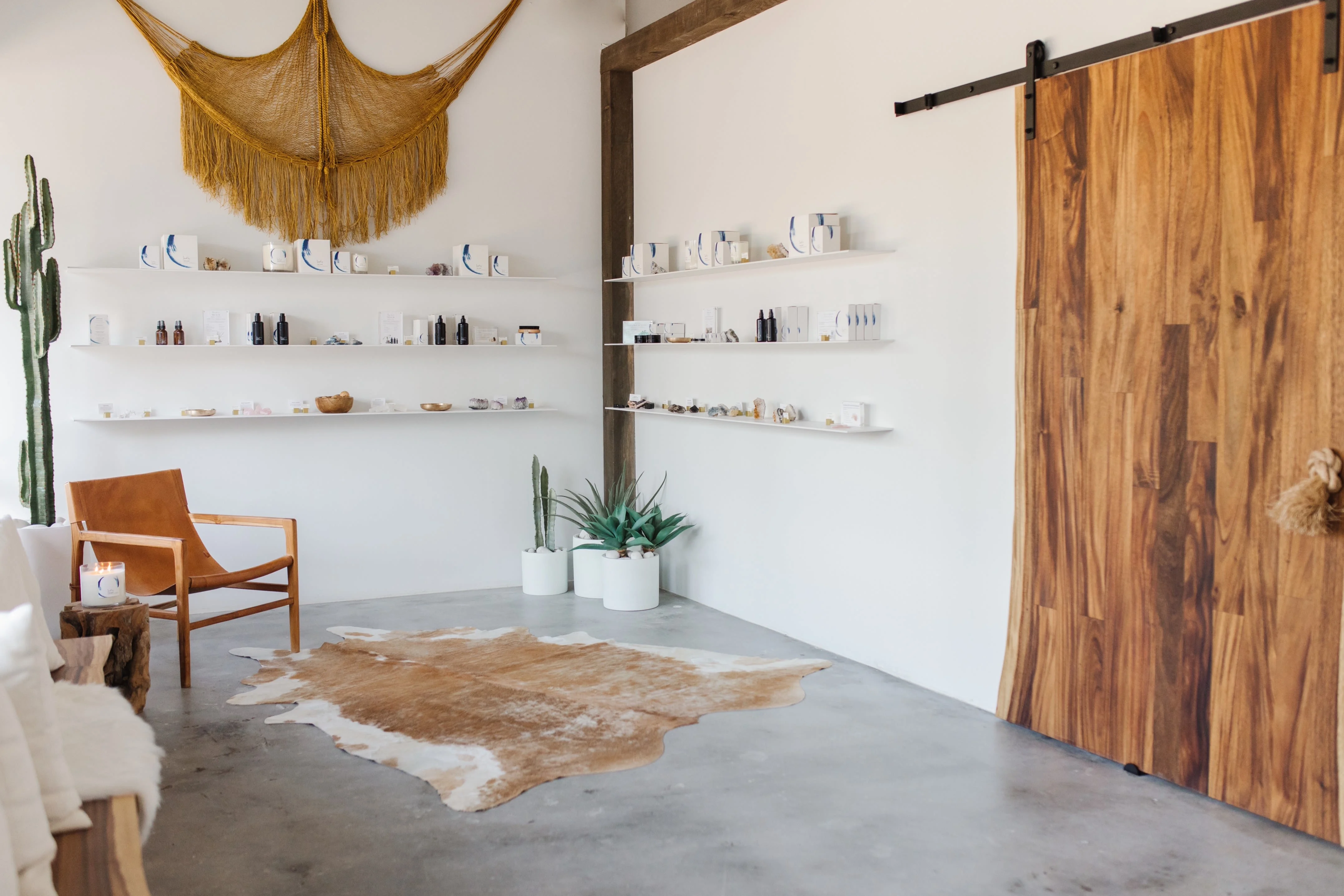 Desert-toned lounge with wall shelves, bench, and sliding door at The NOW Massage Phoenix Camelback