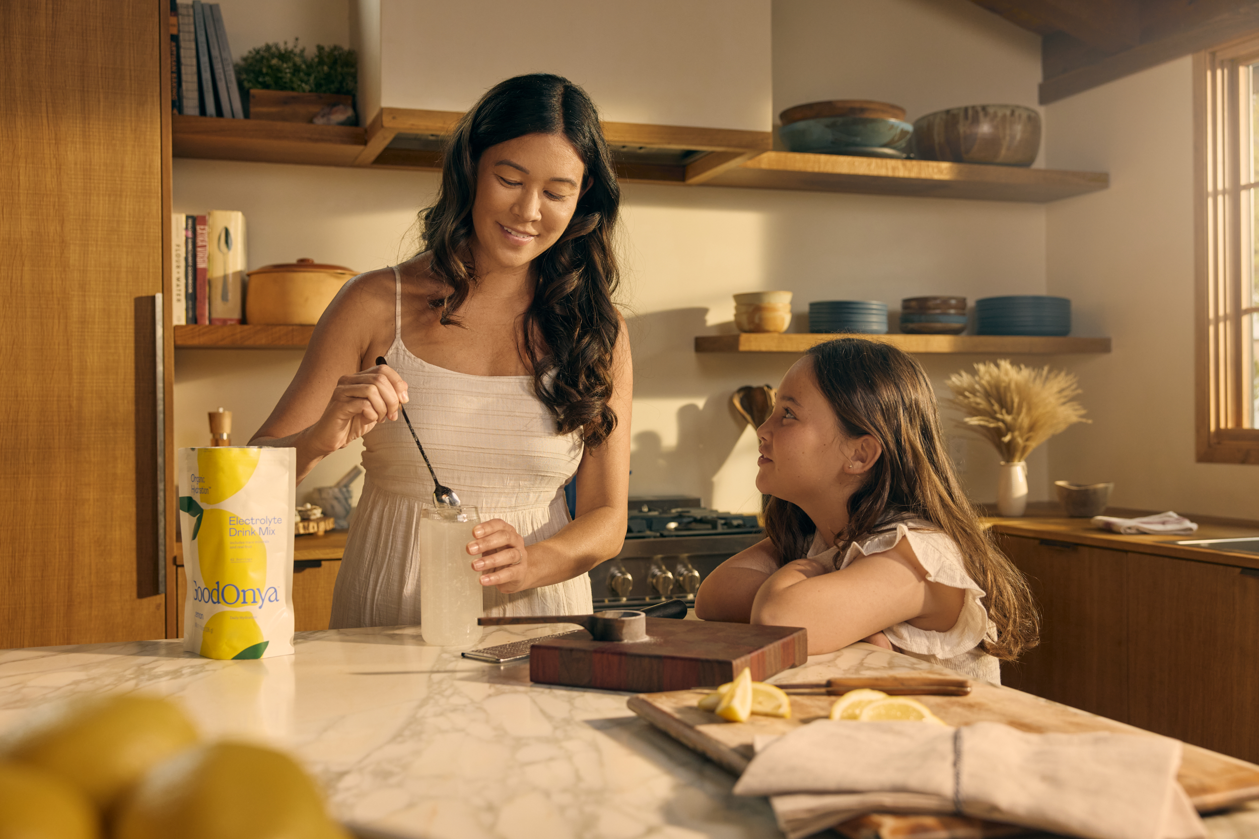 Woman and child preparing a Goodonya electrolyte drink with a canister on the counter.