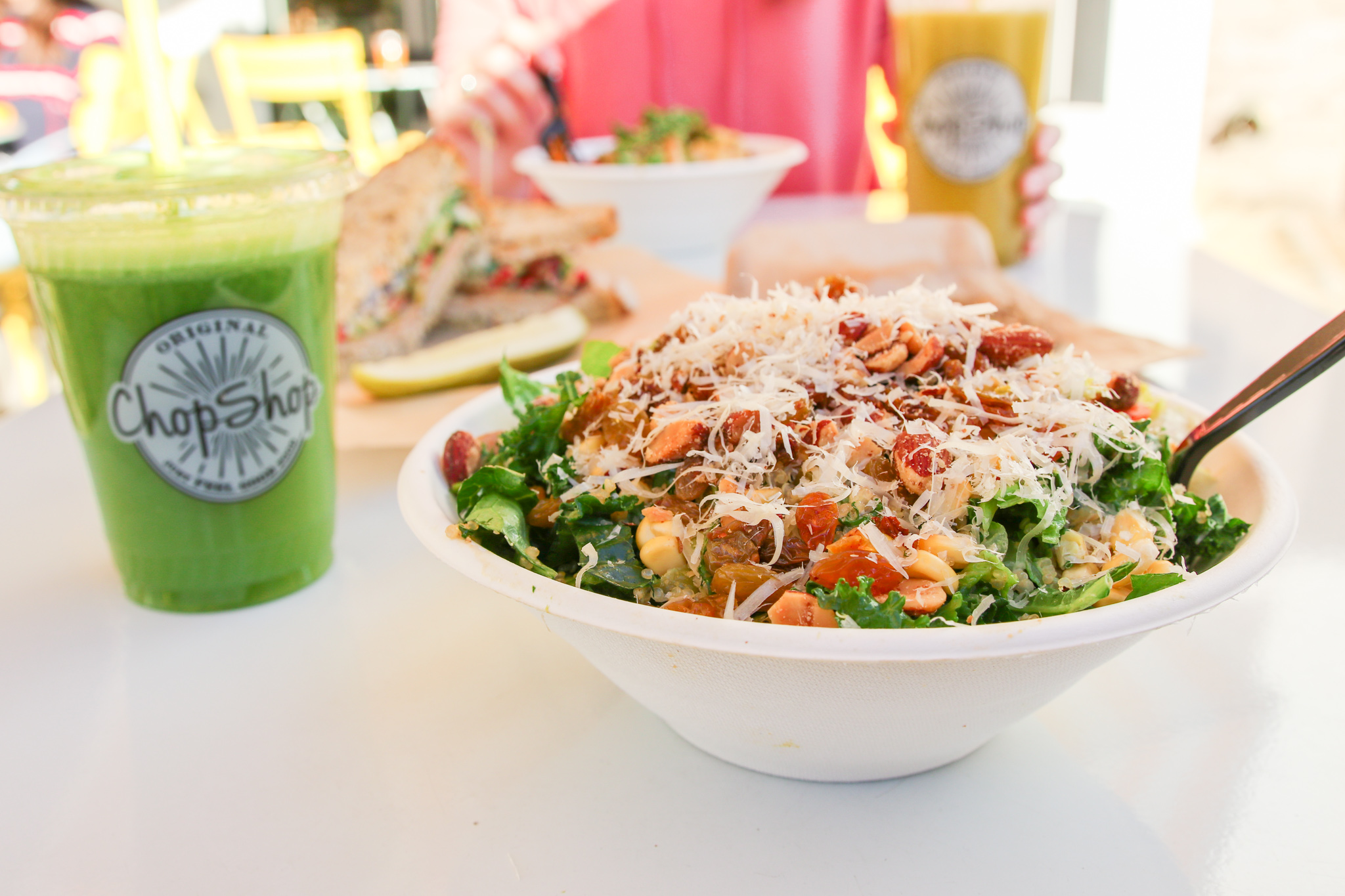 Protein bowl topped with veggies beside a green juice at Original ChopShop Buckhead Atlanta.