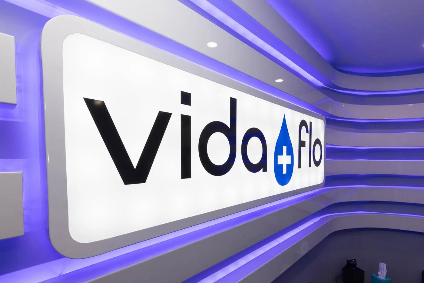 Illuminated Vida-Flo logo sign on purple LED wall at Decatur Atlanta studio.