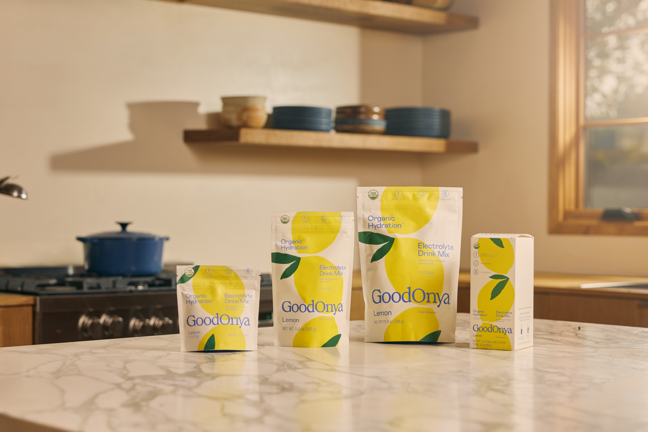 Goodonya Organic Electrolytes lemon canisters on a kitchen counter beside a glass.