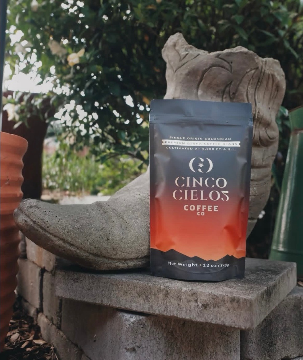 Cinco Cielos Colombian Gesha coffee bag on a wood stump outdoors.
