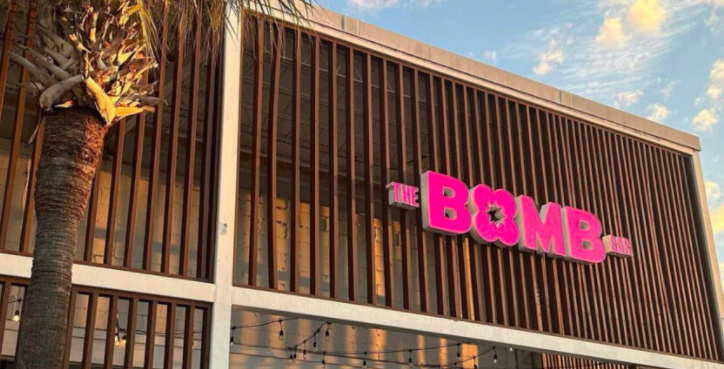 Angled shot of Bomb Bar wooden-slat exterior with bright pink sign.