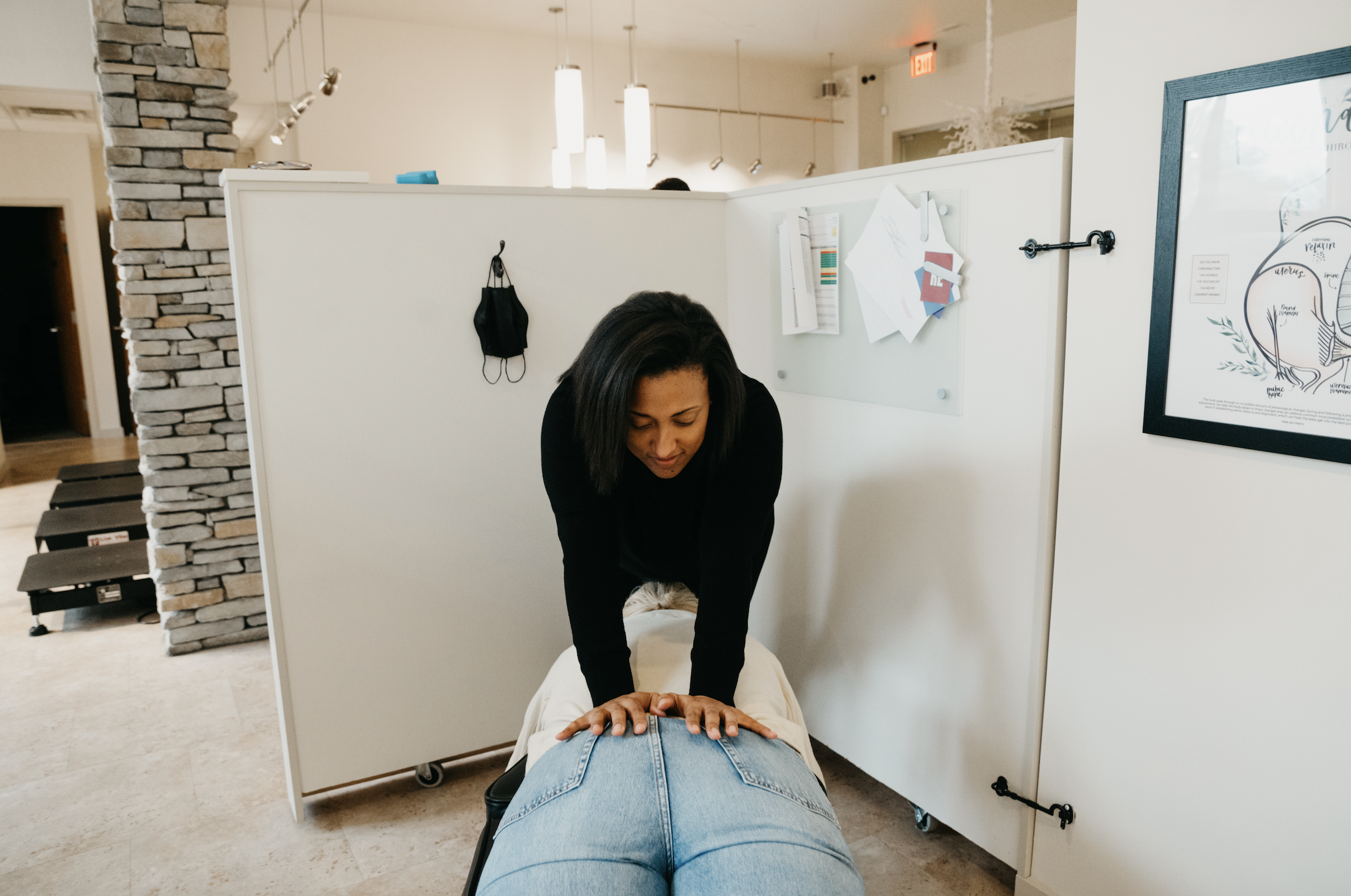 Patient lying face down on a treatment table while the chiropractor performs a spinal adjustment.
