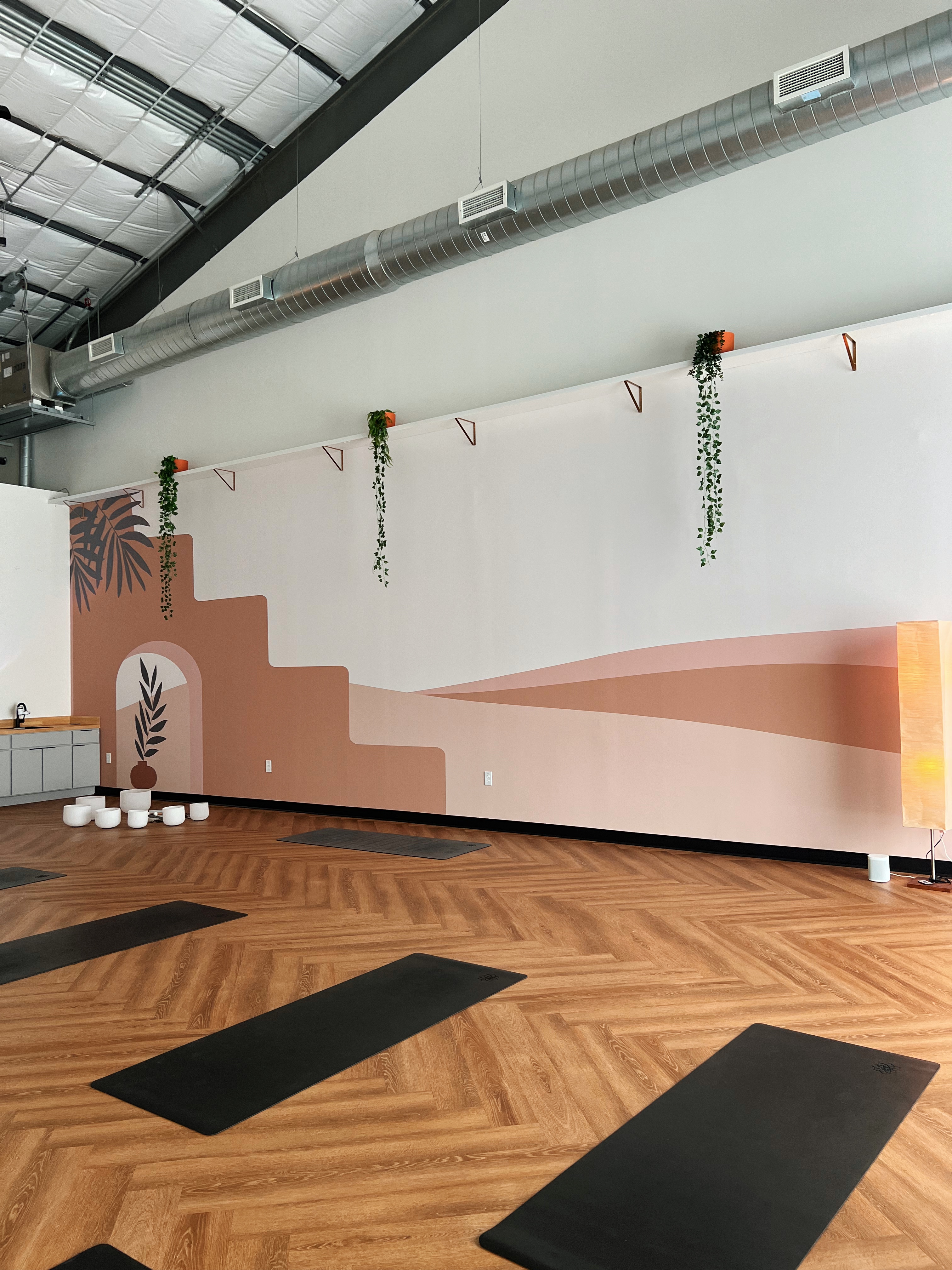 Sunlit yoga space with herringbone floor and two mats laid out at My Vinyasa Practice Highland Austin.
