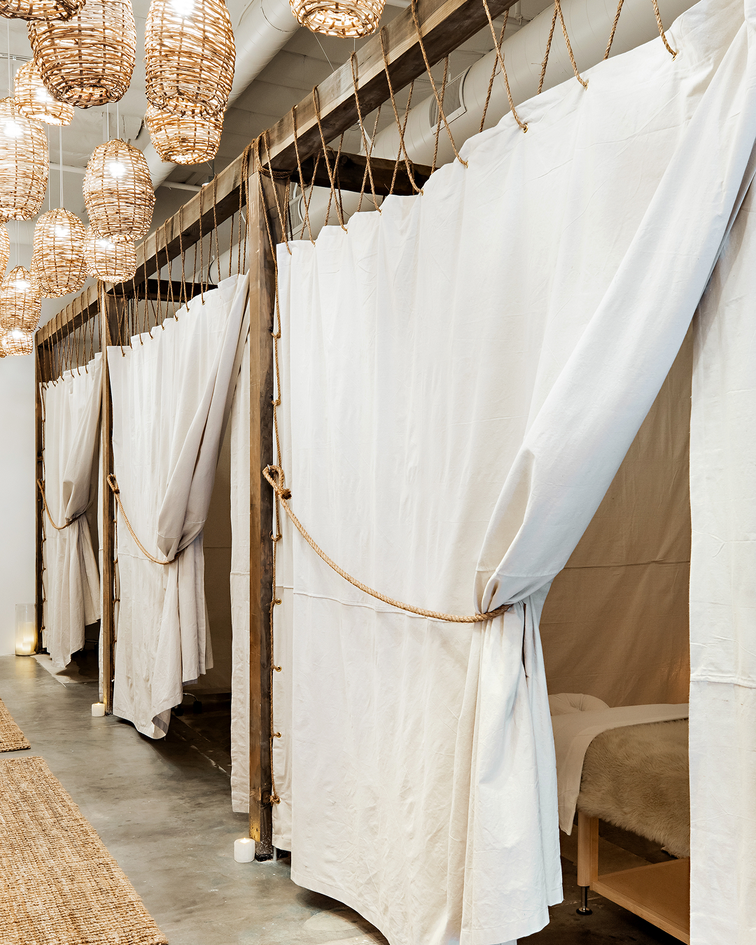Linen-curtained treatment corridor with basket lights at The NOW Massage Mount Pleasant.