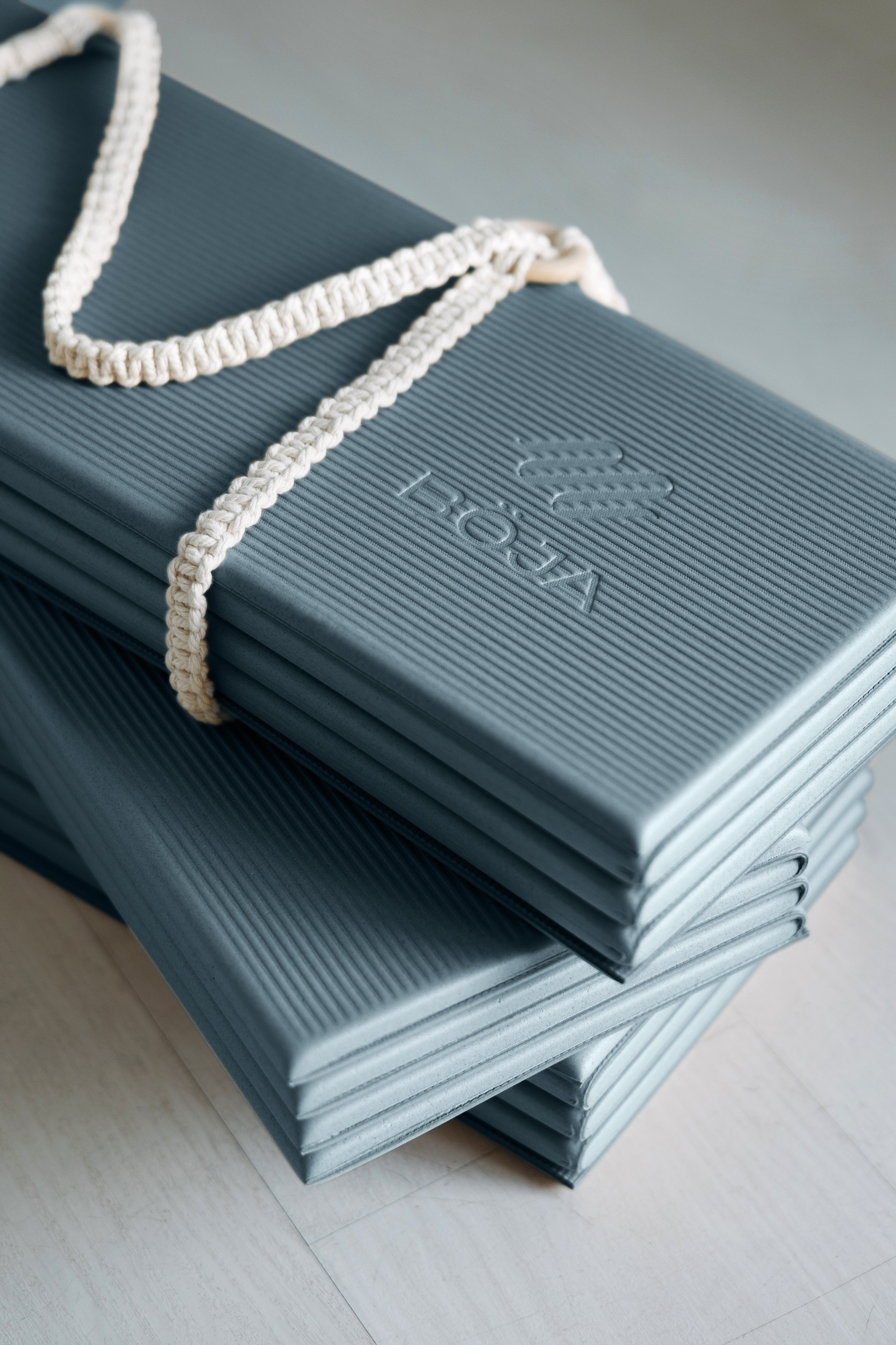 Stack of teal BOJA foldable yoga mat boxes with rope handles, ready for shipment.