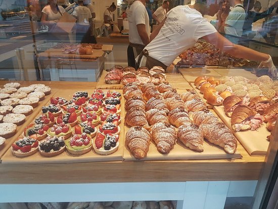 Pastry chef filling display with assorted Italian pastries.