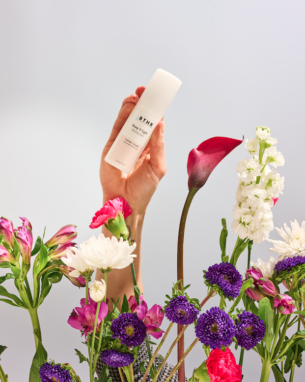 BTHR Keep It Light Moisturizer pump bottle on a pedestal with garden flowers