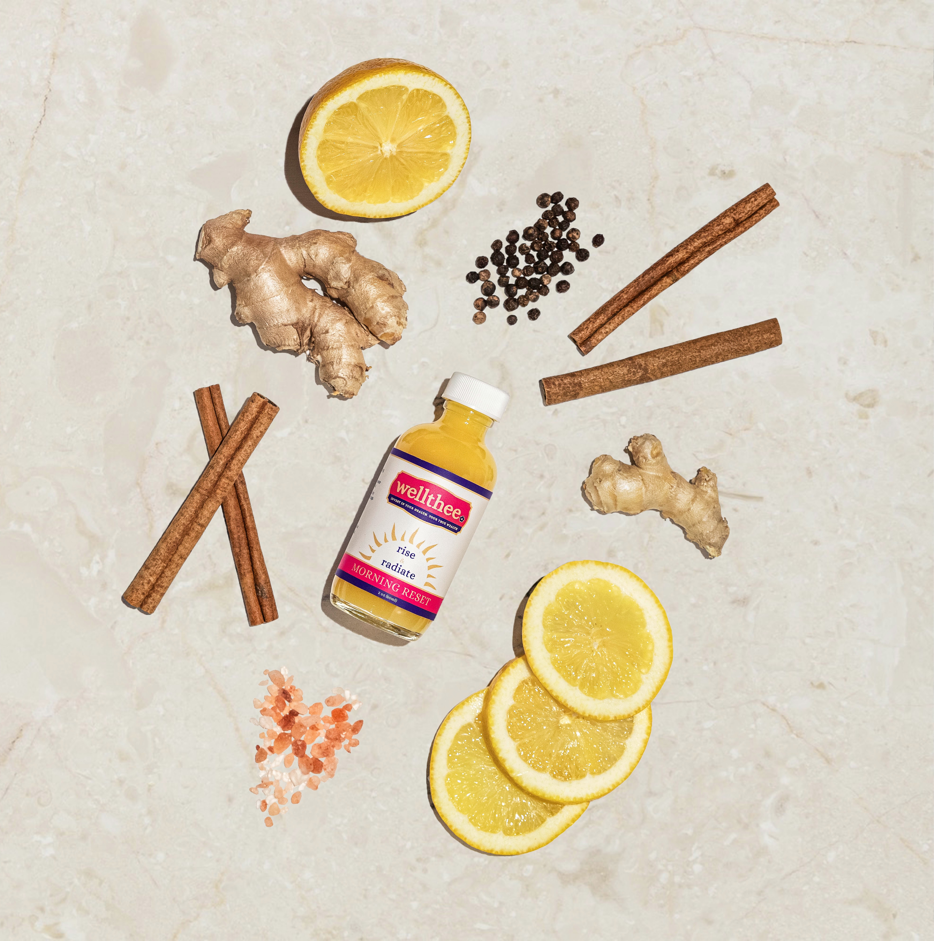 Overhead flat lay of Morning Reset bottle with ginger, turmeric, cinnamon and lemon