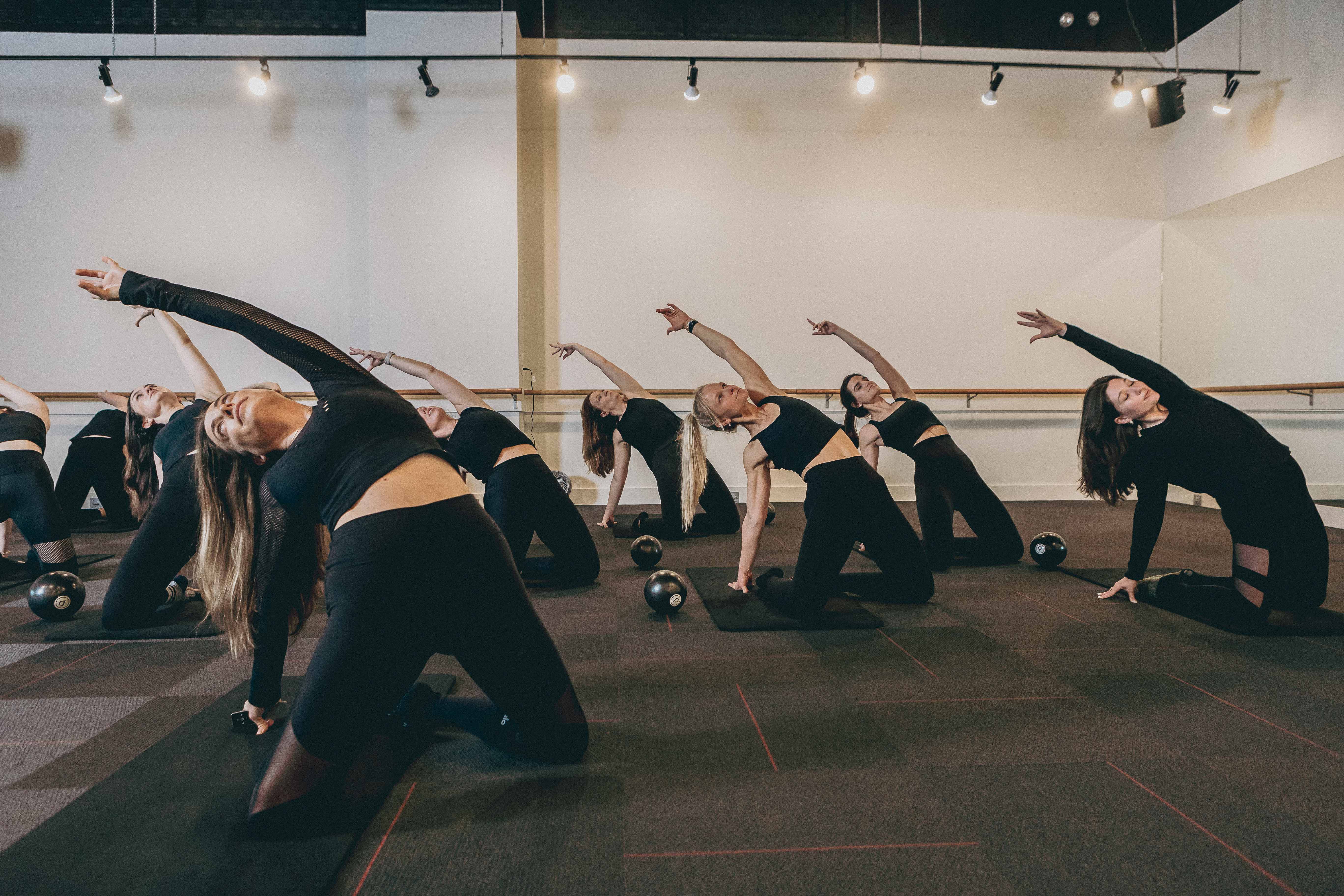 Group performing bridge series on mats in Pure Barre Charleston Downtown studio