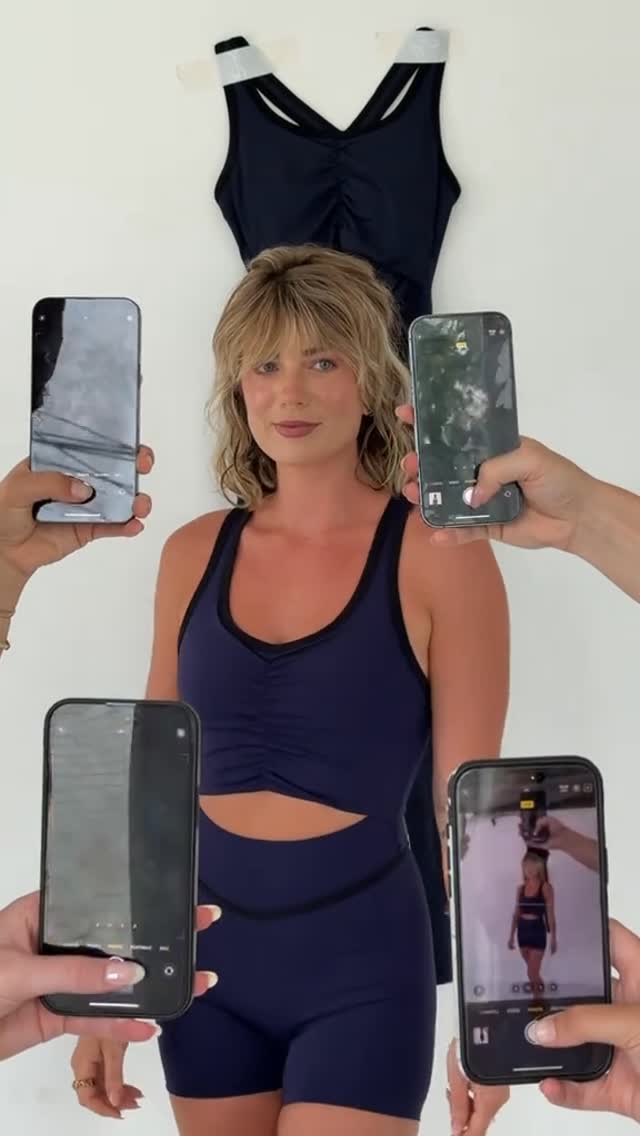 Woman taking mirror selfie in full navy activewear set.