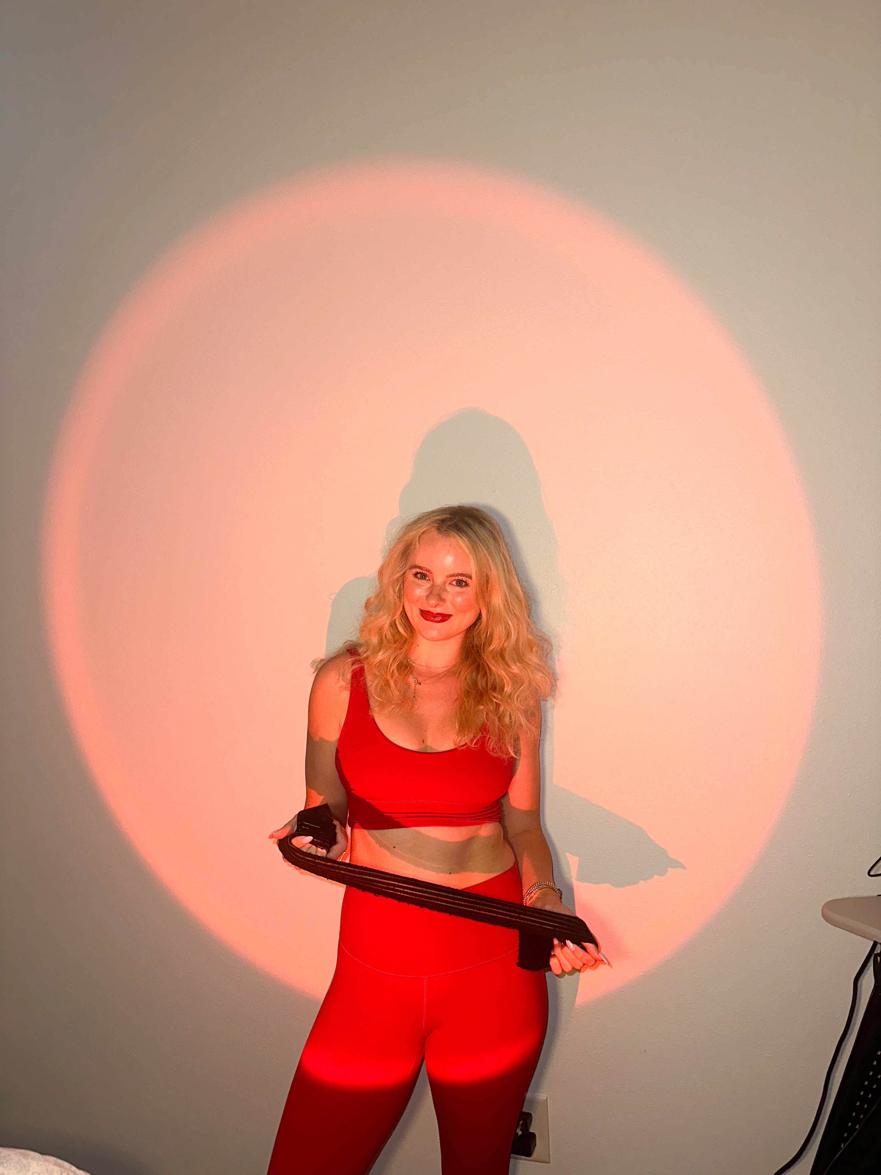 Woman standing and presenting a handheld red light therapy panel at Glow with Gracyn Buckhead.