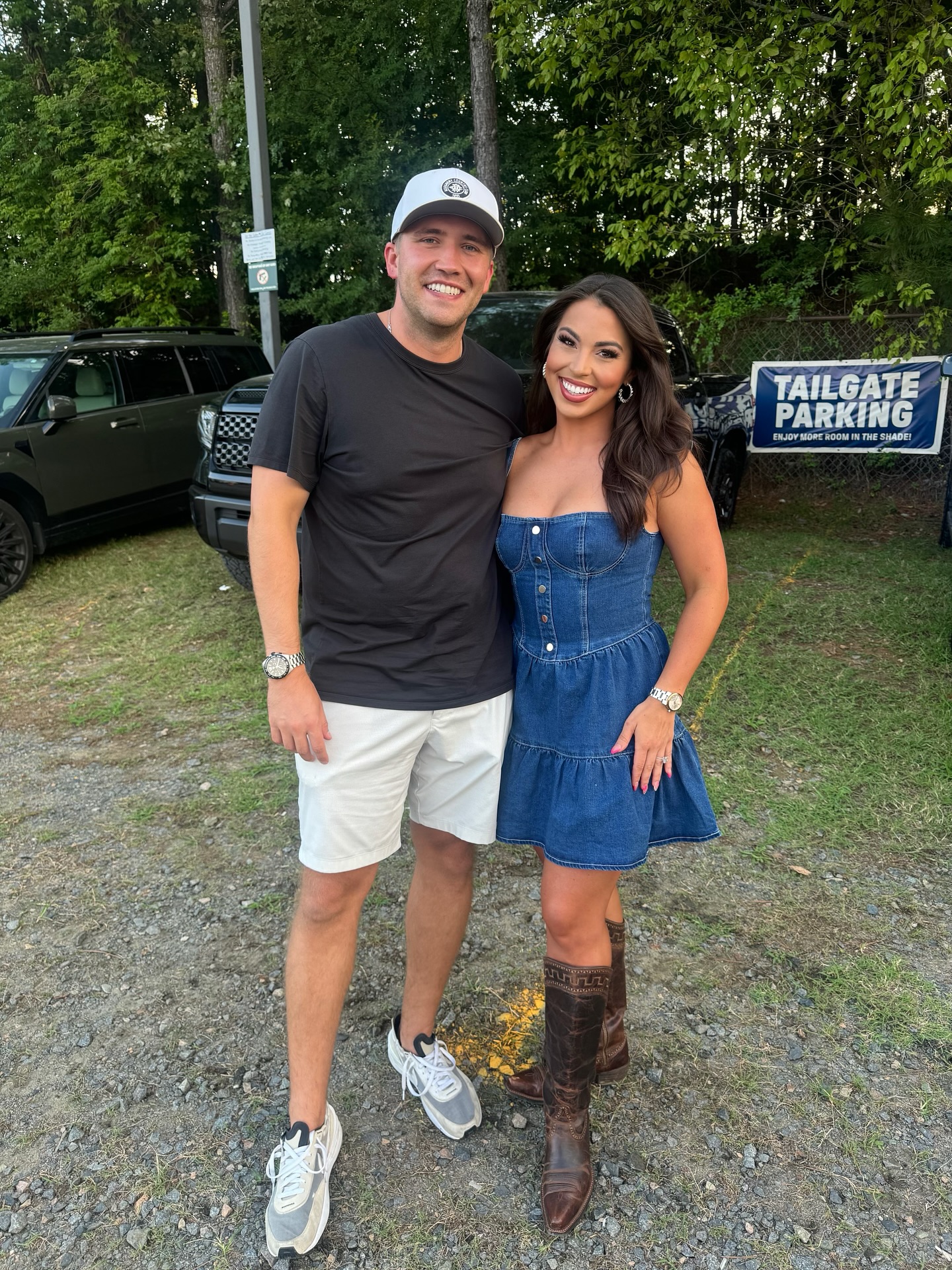 Smiling couple outdoors; woman in denim dress with natural spray-tan glow – Muse Tan Atelier South End Charlotte