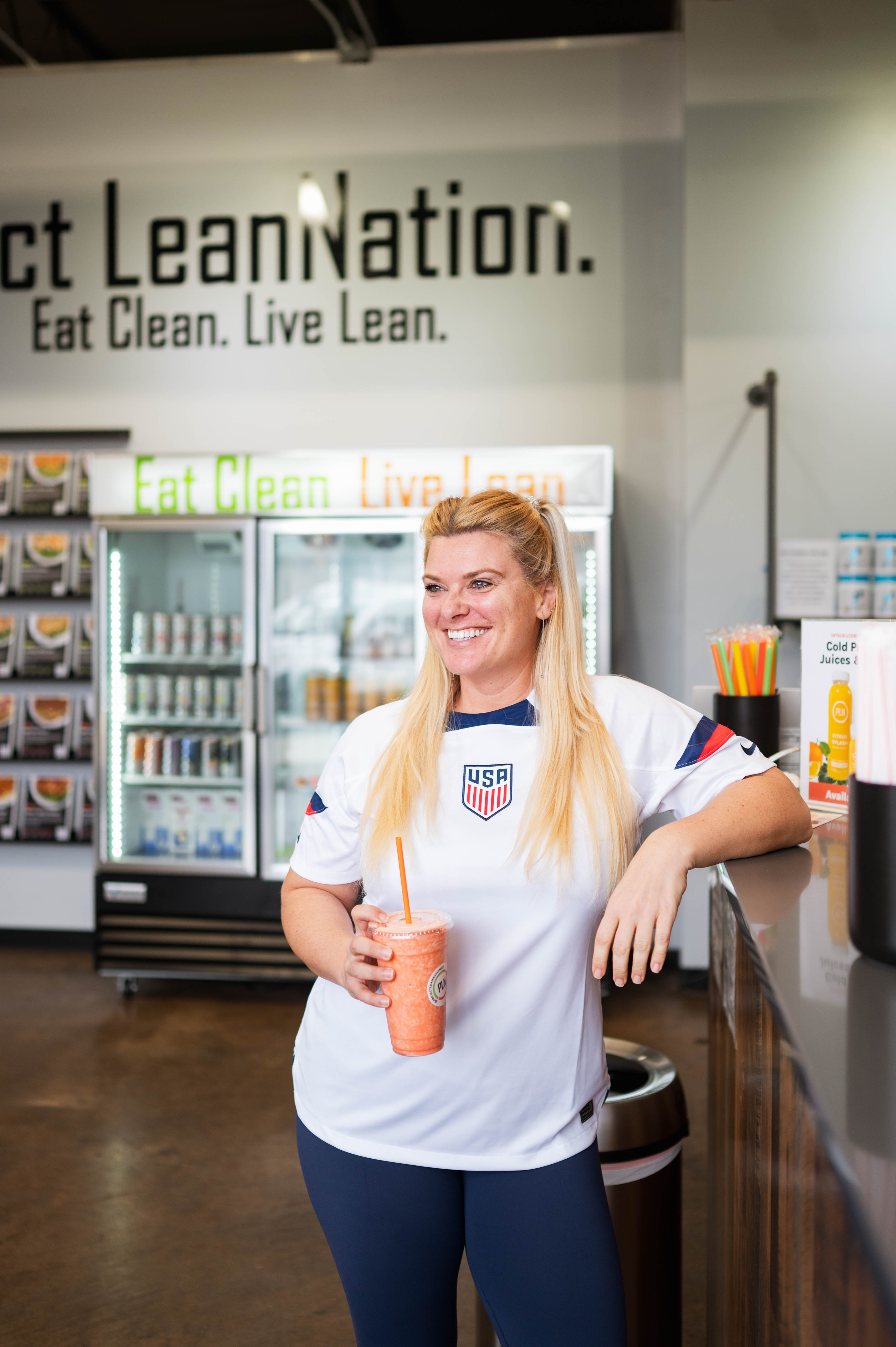 Smiling team member by a fridge filled with Project LeanNation prepared meals at South End Charlotte.