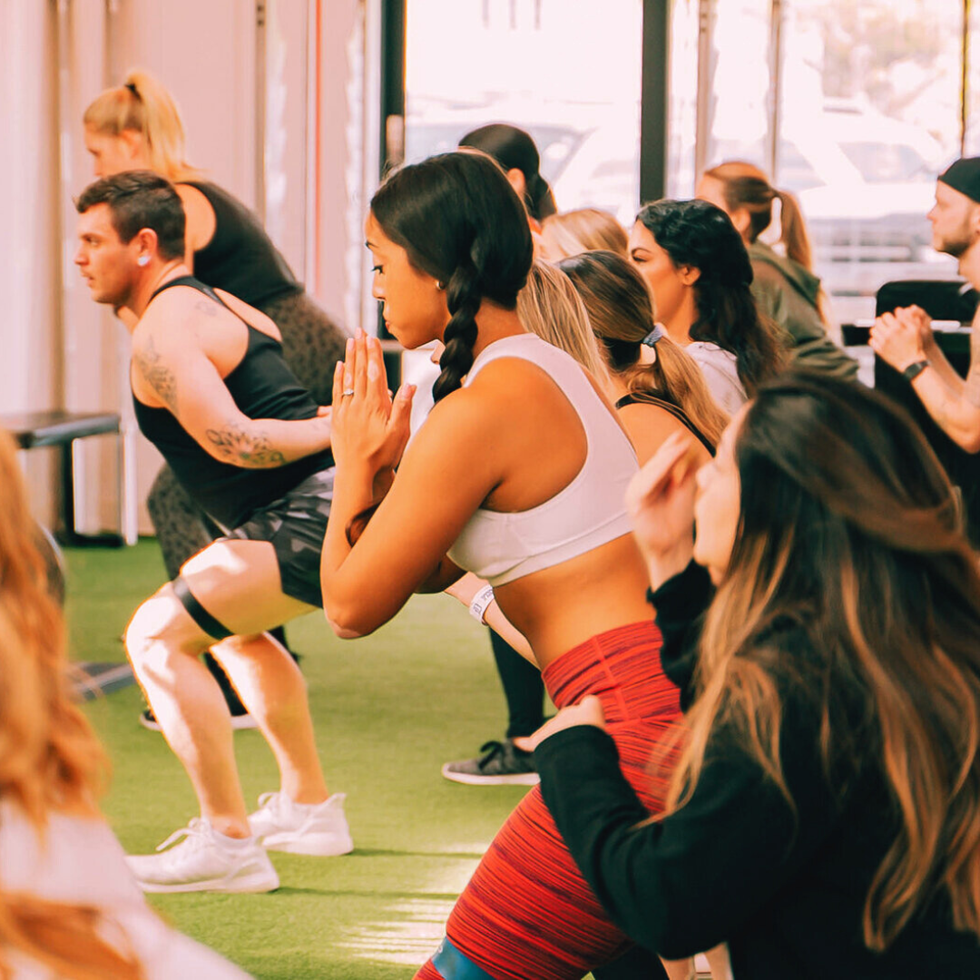 Group of women performing tempo squats with coach instruction at Peach Lab Charleston fitness studio.