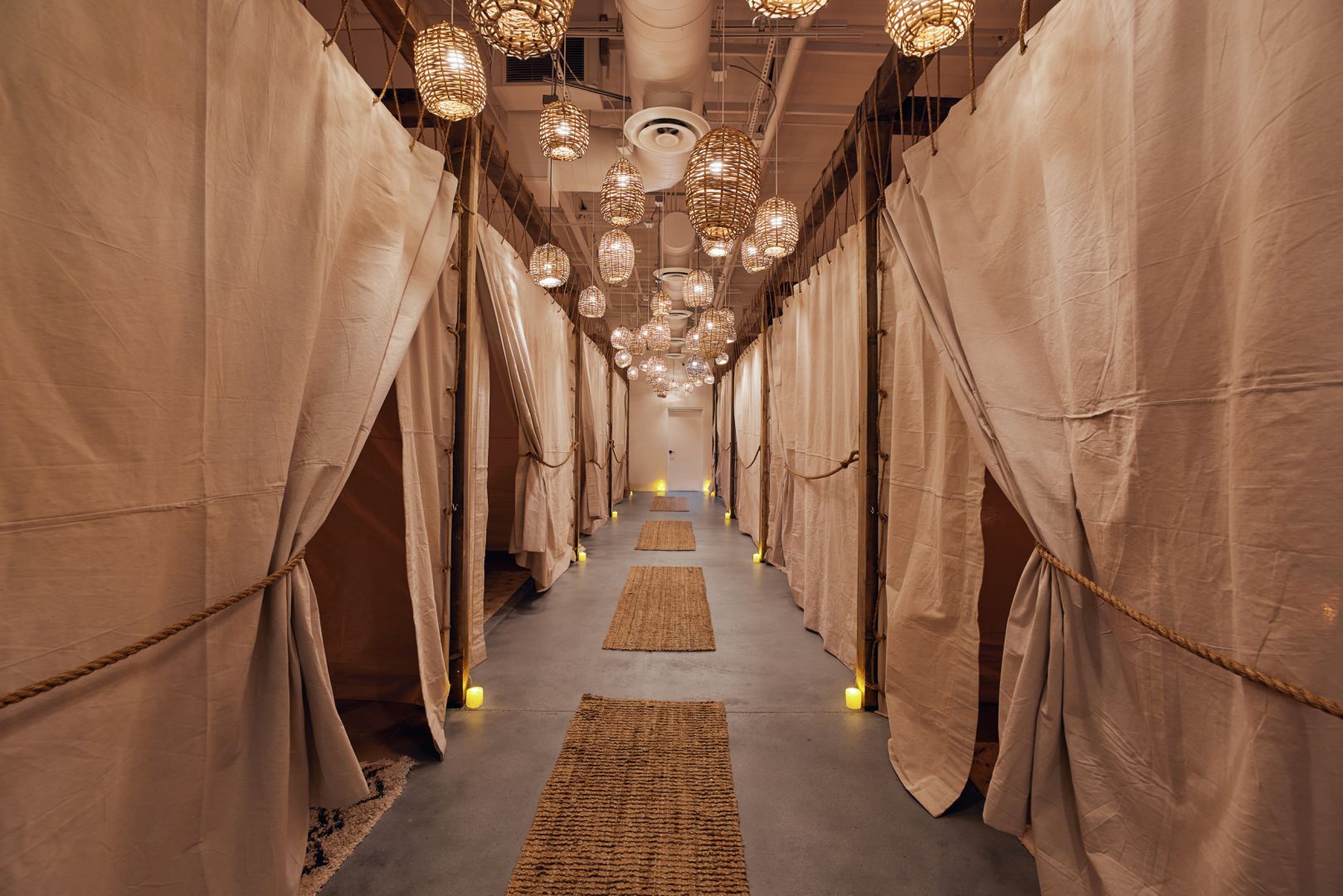 Linen-canopied hallway with pendant lanterns at The NOW Massage South Lamar Austin.