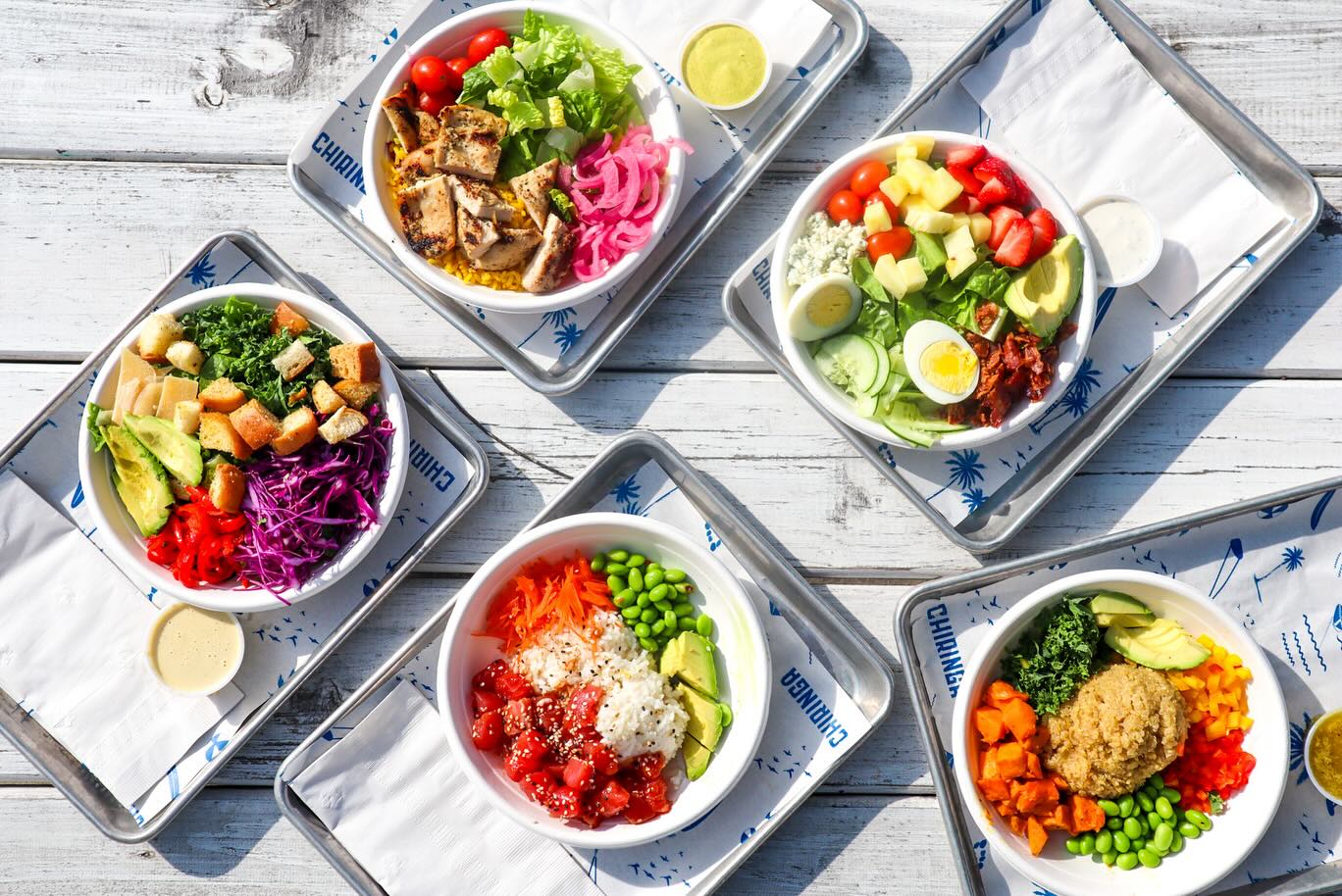 Overhead of four fresh bowls with colorful toppings at Chiringa O4W