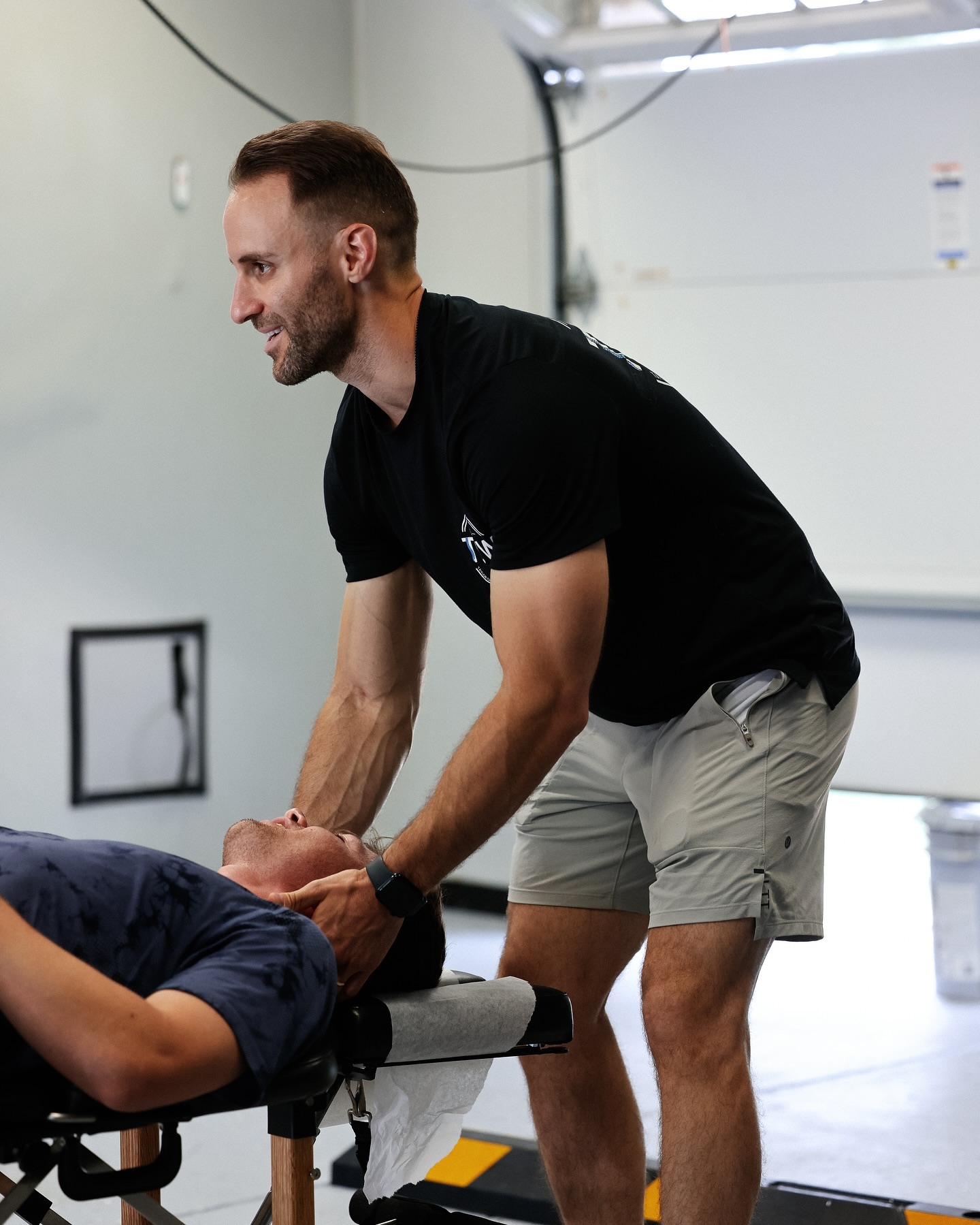 Chiropractor assisting athlete in movement drill during rehab session.