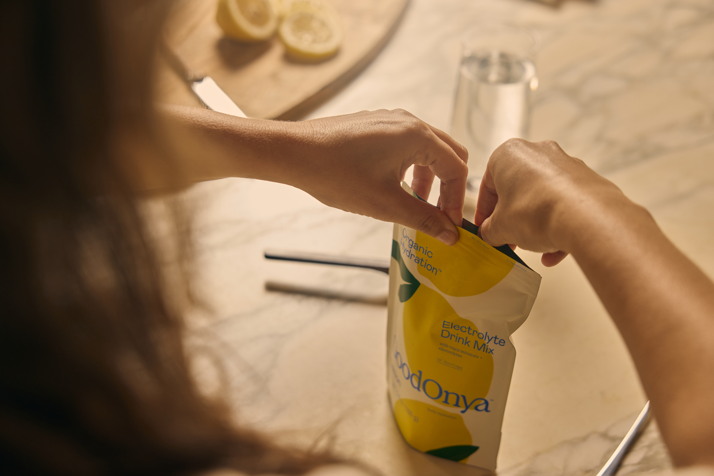 Hands opening a yellow Goodonya canister to scoop electrolyte powder.