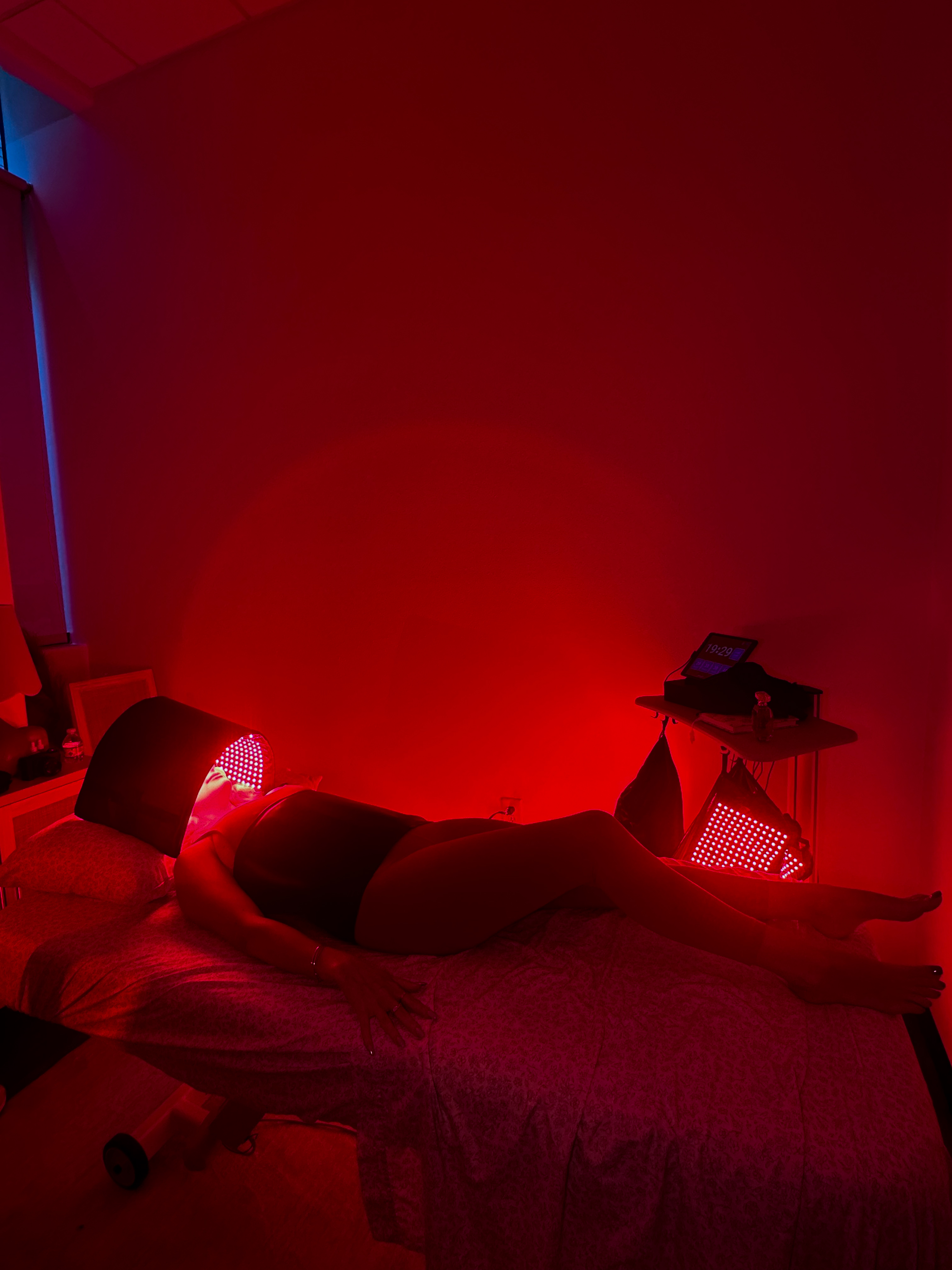 Person lying on a treatment bed illuminated by red light therapy in Buckhead clinic.