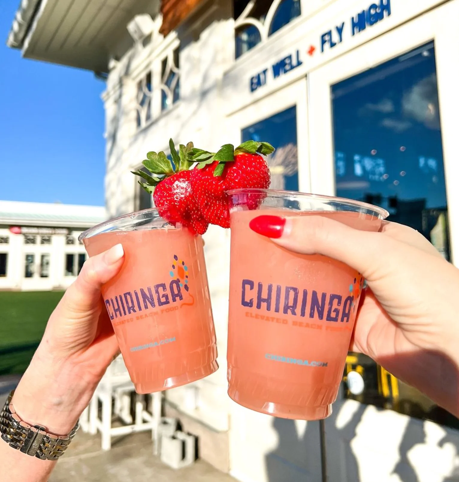 Two frozen cocktails with CHIRINGA cups held outside the restaurant