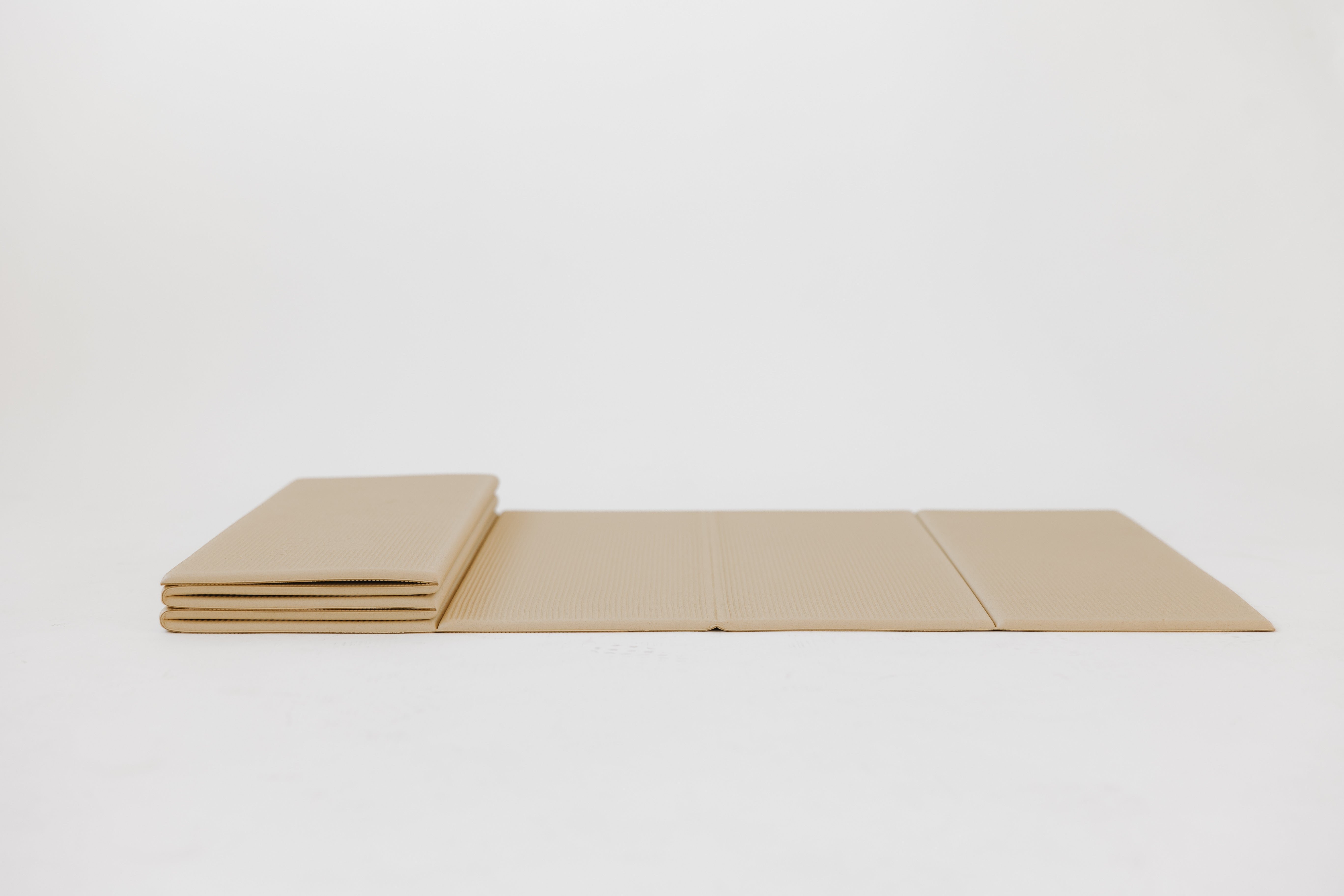 Flat-lay of fully unfolded BOJA foldable yoga mat highlighting crease pattern and thin cushioning.