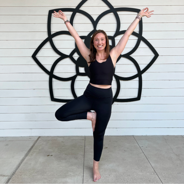 Yoga instructor in tree pose before black lotus mural at My Vinyasa Practice Highland Austin.