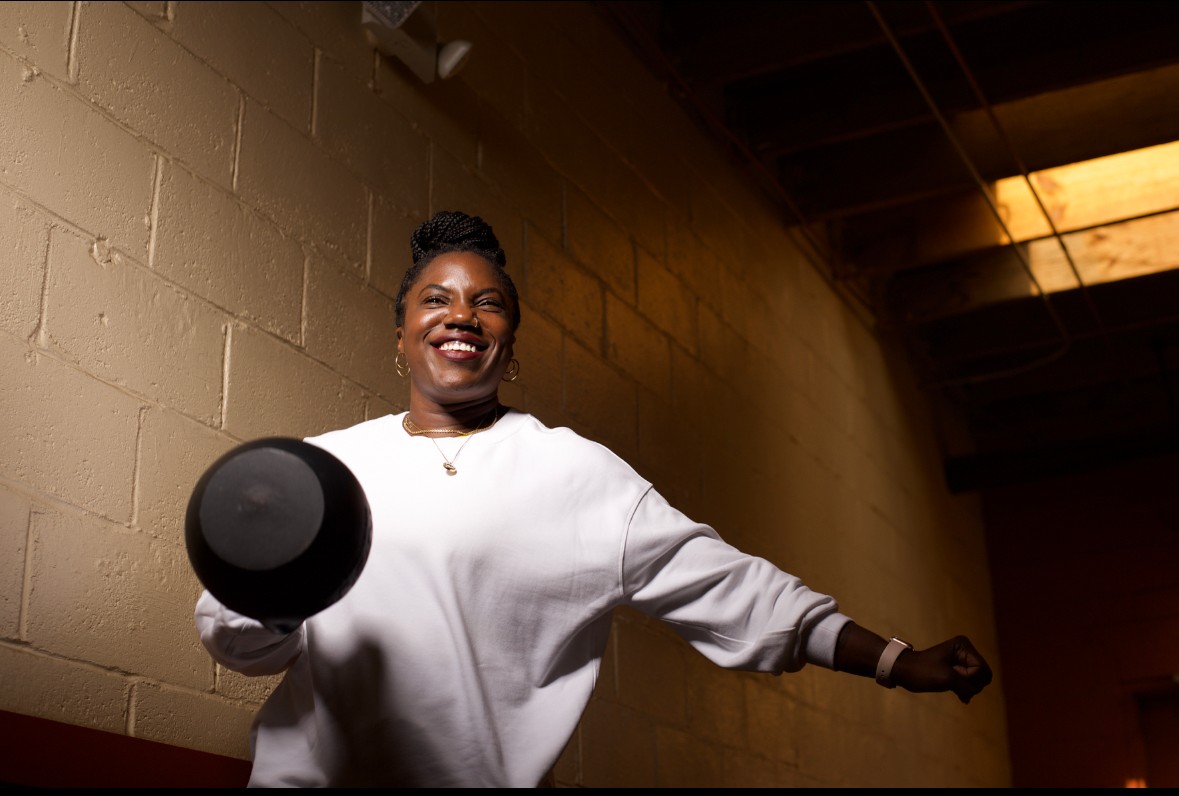 Smiling athlete holds medicine ball in brick hallway after interval workout at MADabolic Atlanta.