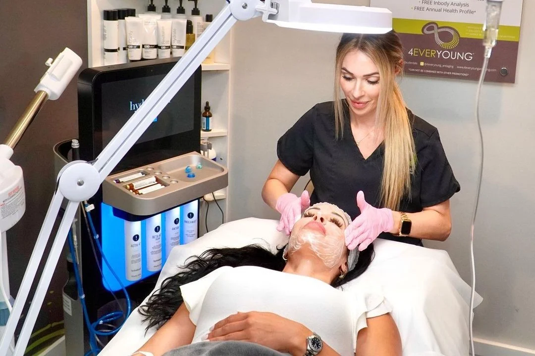 Provider performing a facial under a magnifying lamp while the client reclines.
