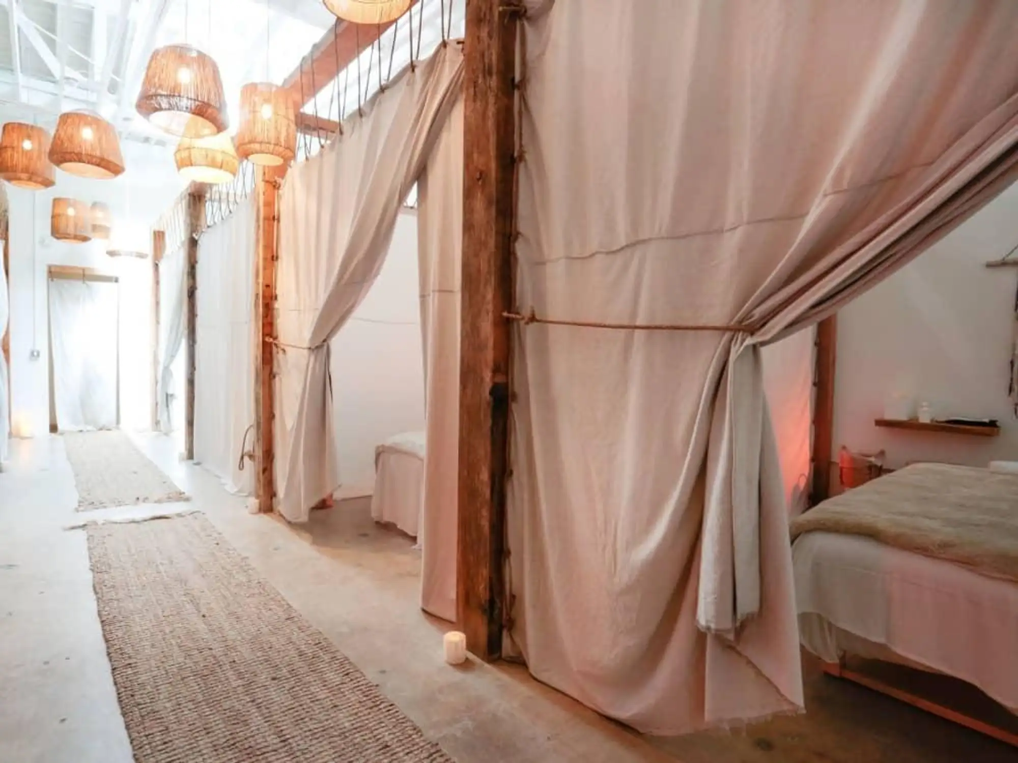 Bright hallway with white curtains and rattan lights inside The NOW Massage South Lamar Austin.