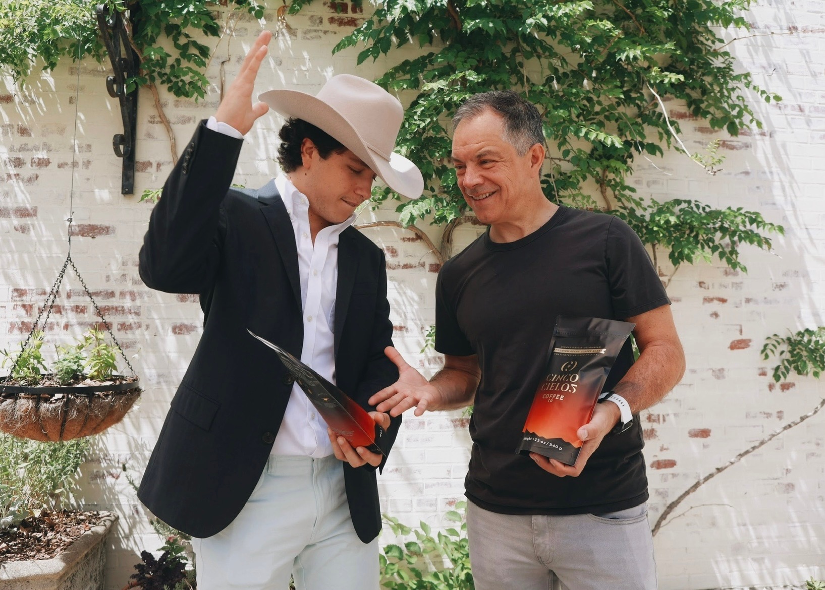 Two people holding a Cinco Cielos Colombian Gesha coffee bag.