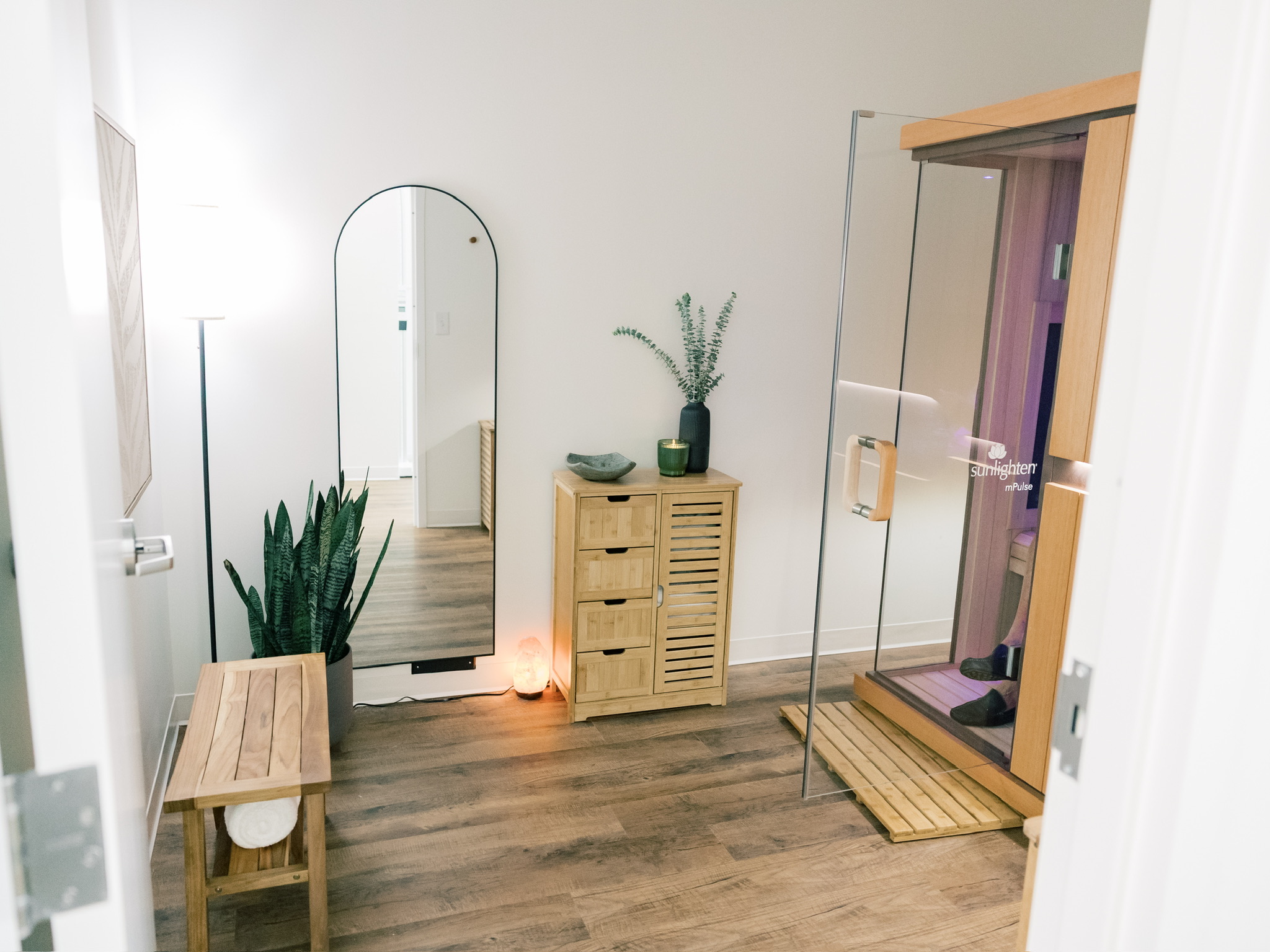Clean prep room with an arched mirror, bench, and plant