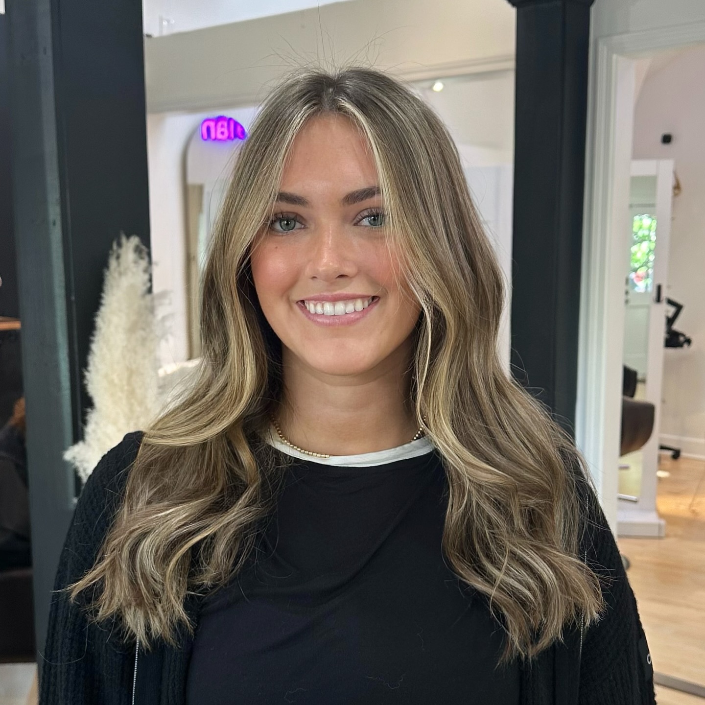 Smiling client with ash-bronde waves inside Kayleigh Aesthetics salon.