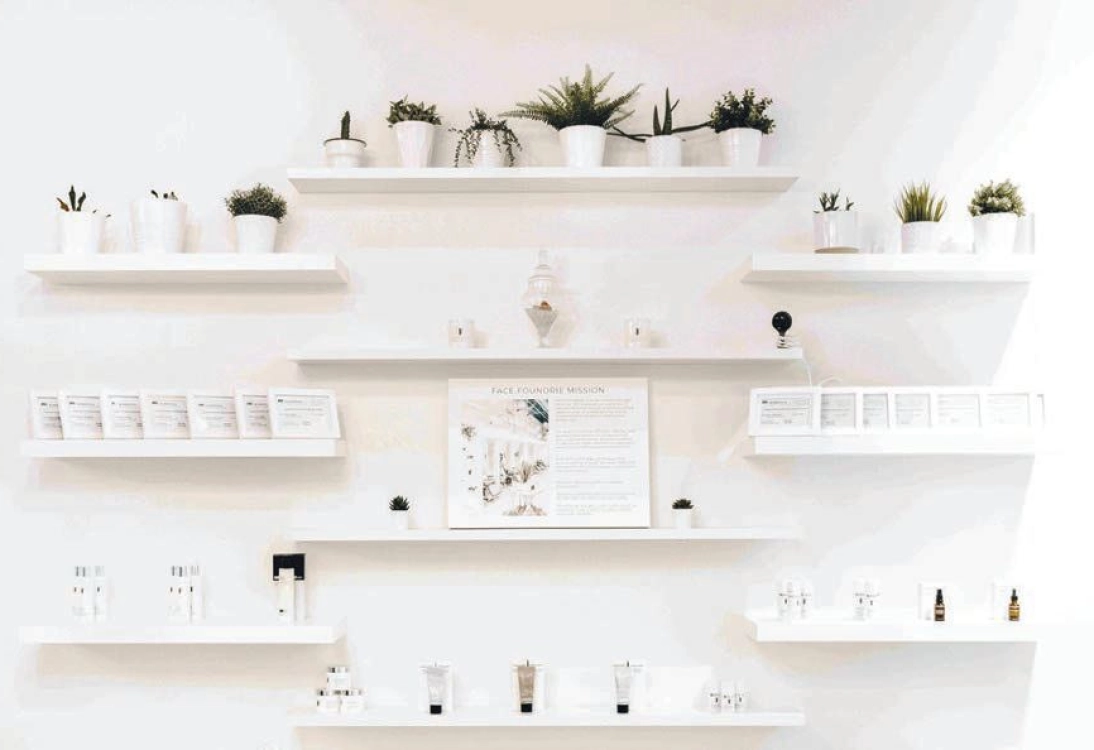 Bright FACE FOUNDRIE Atlanta retail wall with skincare products styled on white floating shelves