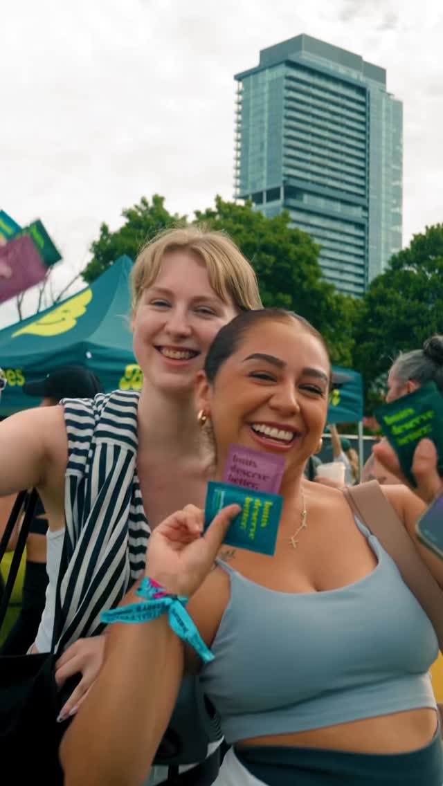 Friends at a music festival holding Goodwipes body wipes, city skyline in background.