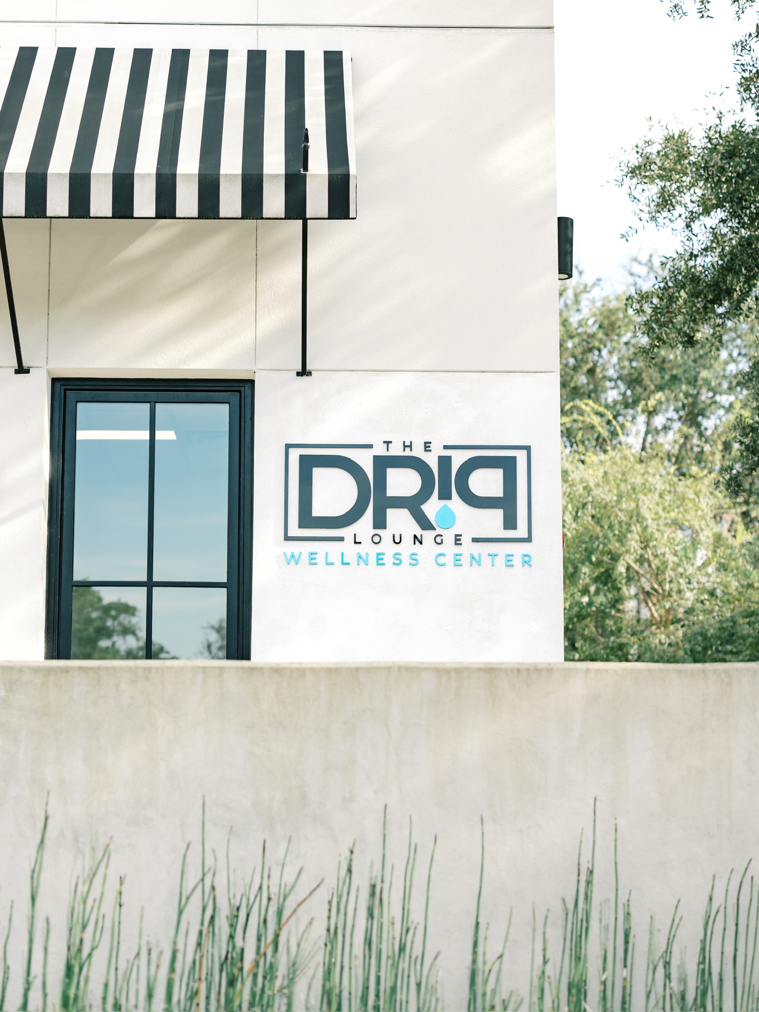 Exterior of The Drip Lounge with striped awning and logo sign