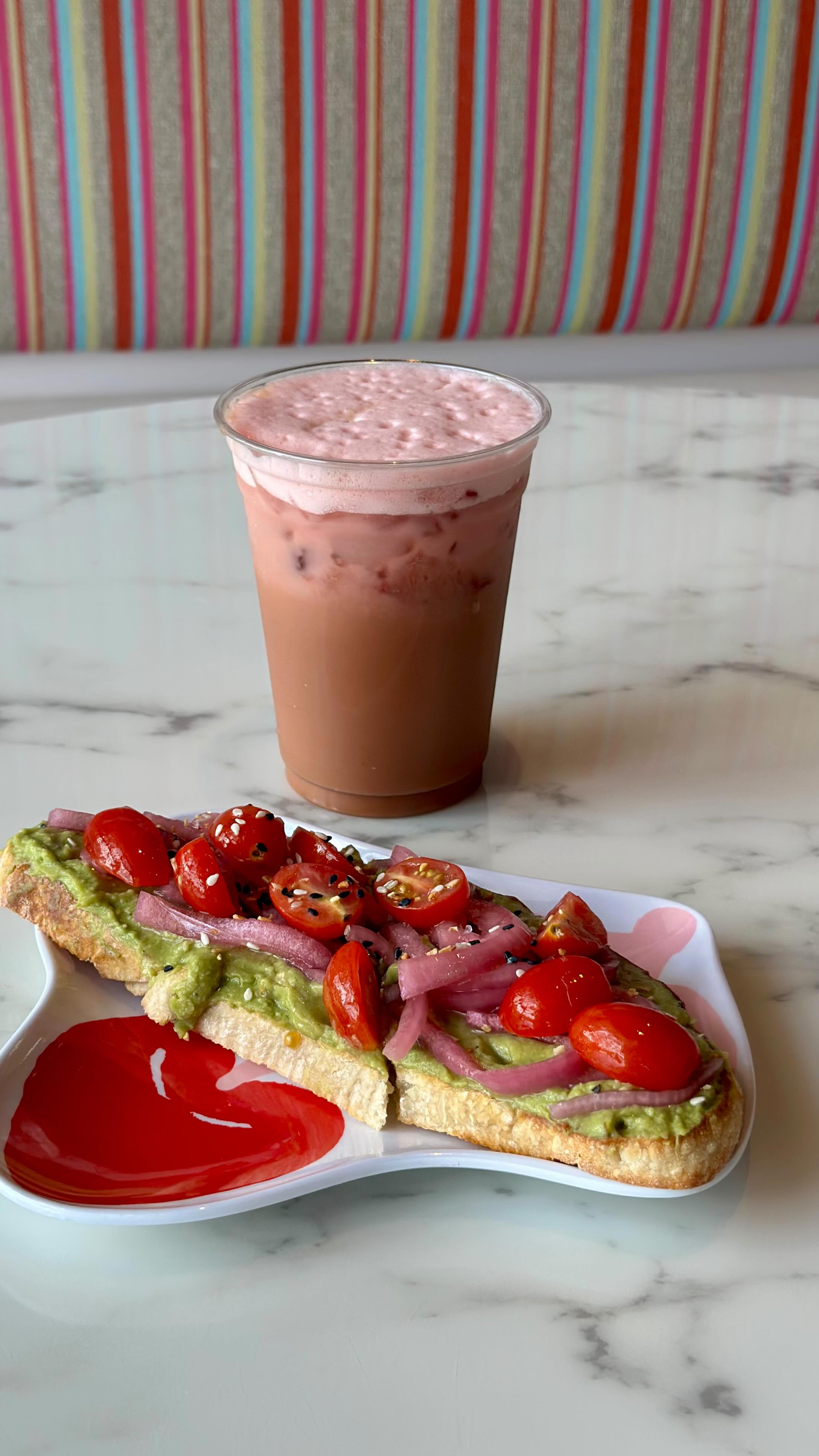 Pink smoothie and pizza slice on marble table at Bomb Bar Charleston.