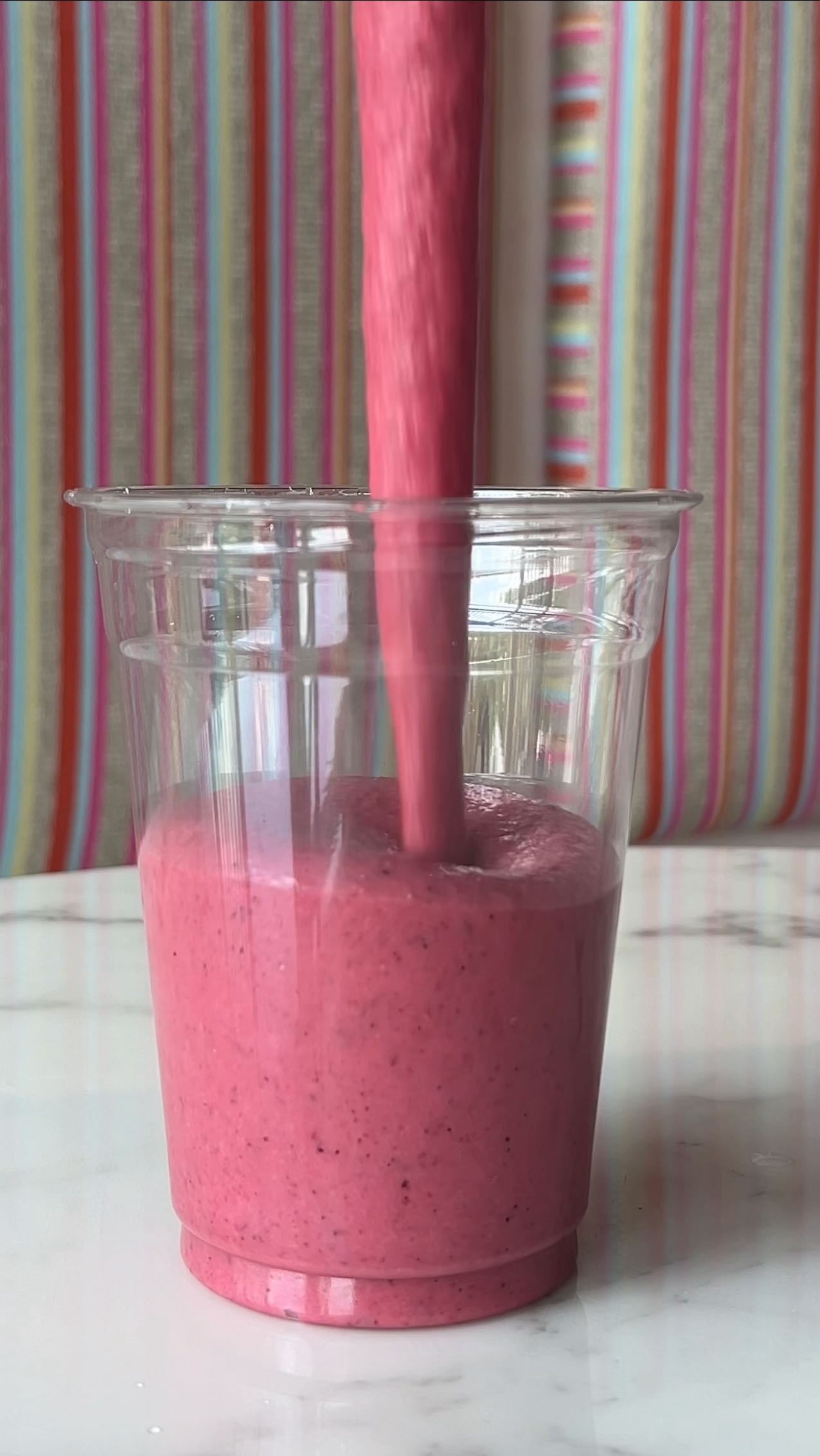 Three tall smoothie glasses with green, pink, and purple blends.