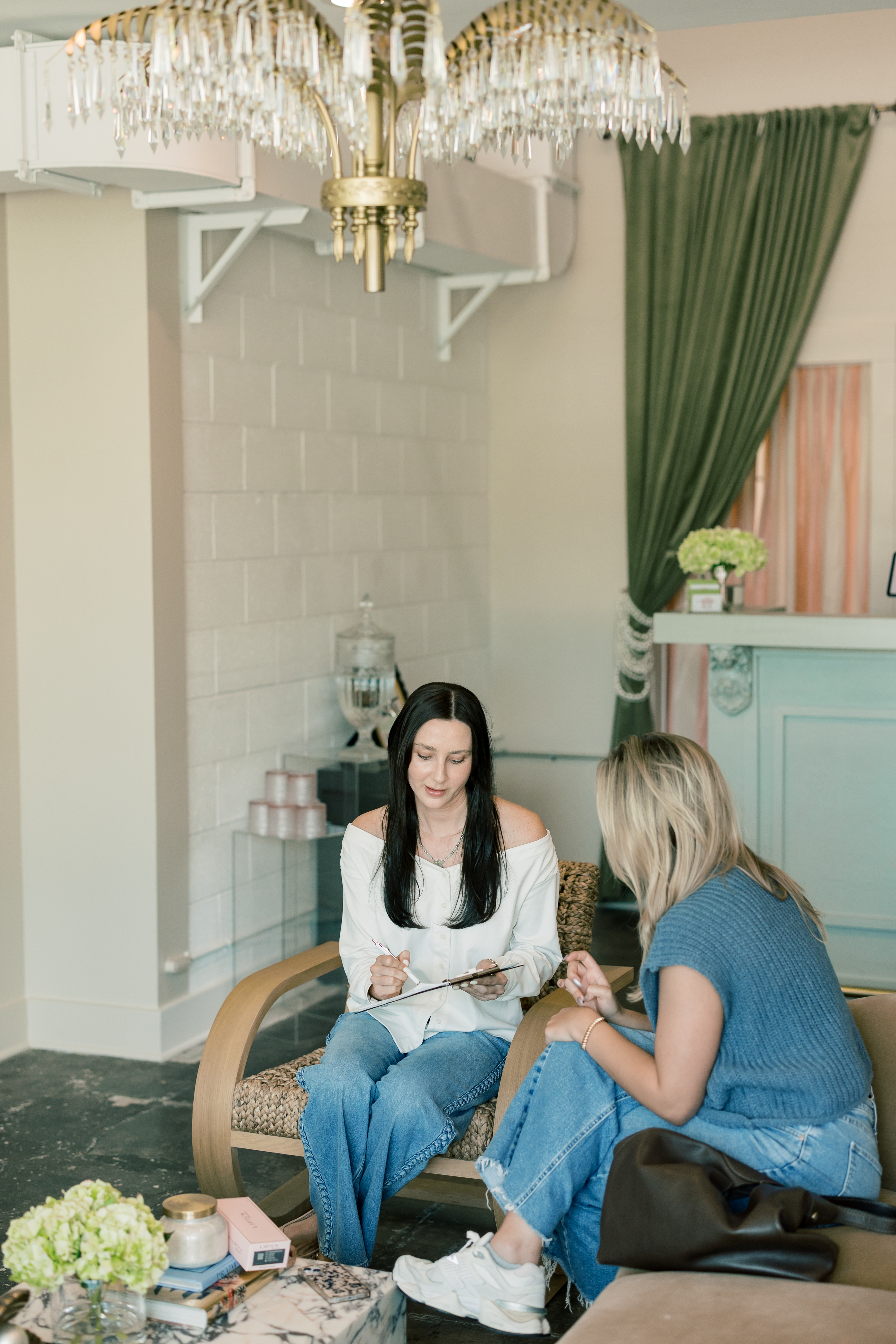 Two guests chatting in the waiting area at Pearl Medspa Charleston.